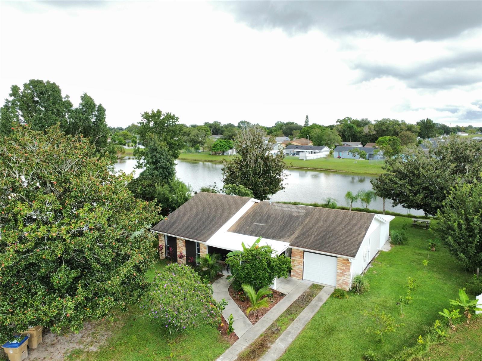 Spacious WATERFRONT property in Buenaventura Lakes with INCOME POTENTIAL—featuring a RENOVATED 5 bedroom 4 bath 1 car garage home which includes TWO fully separate IN-LAW suites or rentals. The two 1 bedroom 1 bath units are currently rental units listed on Airbnb for immediate monthly income. Situated on one of the LARGEST LOTS in the neighborhood, this private park-like setting offers direct lake access, lush tropical landscaping, and more than 20 mature fruit trees including mango, jackfruit, orange, grapefruit, banana, fig, pineapple, and coconut palm. Outdoor living shines with a built-in barbecue, picnic table with natural shade from a tree, and plenty of space for gatherings. The main home has been beautifully updated with large-format tile throughout, elegant marble countertops, a spacious kitchen island, and modern bathrooms with high-quality finishes. A dedicated laundry room for the rentals keeps the main home private. Set on a quiet cul-de-sac with friendly neighbors, this property also offers expansion potential or possible space to build another home (buyer to verify with city and zoning). Enjoy peaceful natural surroundings while being just 20 minutes to Disney, 18 minutes to Orlando International Airport, and 20 minutes to Universal and major outlet malls. Shown by appointment only, so be sure to schedule a time to see it in person or enjoy a video tour and make an offer before it's gone. NEW ROOF will be put on before closing.