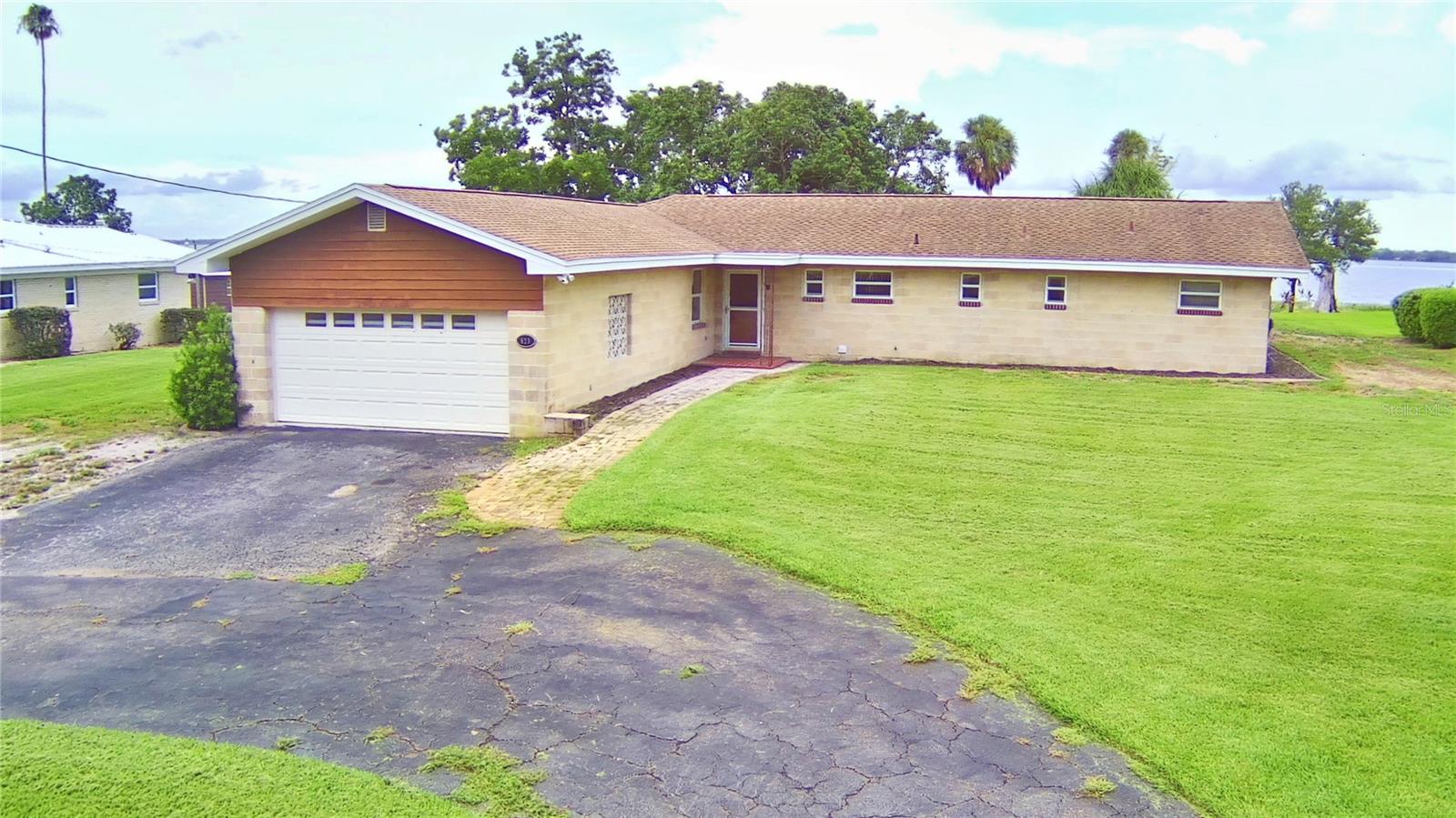 MAGNIFICENTLY REMODELED TO OPEN UP THE LIVING/DINING/KITCHEN AREA FOR ONE LARGE GREAT ROOM! YOU WILL LOVE THIS ARRANGEMENT! AS YOU STEP INTO THE FRONT DOOR THERE IS A HALL CLOSET TO YOUR LEFT AND A HUGE OPEN ROOM WITH VIEWS TO LAKE REEDY, KNOWN FOR IT FANTASTIC FISHING, WATER SPORTS, AND IS FAA APPROVED! This 3 bedroom 2 bath home with 21x22 car garage sits on an acre with breath-taking views across LAKE REEDY! Wake up every morning with beautiful views of LAKE REEDY from all 3 bedrooms, the kitchen, living and dining areas! What a great OPEN CONCEPT layout starting with the recently remodeled kitchen equipped with wood cabinets, stainless-steel appliances, granite countertops, cook top range, wall oven & microwave as well as a MASSIVE ISLAND ideal for prepping meals and entertaining guests! The hall bath was very recently remodeled! The spacious primary bedroom has a walk in closet and a shower en suite. Entertain from your large back porch OR fish from your own dock! The yard has fruit bearing trees such as avocado and sweet mangoes! The central air/heat system is about 2 years old! IDEALLY LOCATED WITHIN 1.5 HOUR DRIVE TO 2 INTERNATIONAL AIRPORTS, MUSEUMS, ATLANTIC OCEAN, GULF OF AMERICA, 30 minutes to Bok Tower, Legoland and a short drive to many, many lakes, State Parks, and golf courses! THIS IS THE PLACE TO BE! CALL US TODAY TO SCHEDULE YOUR VIEWING!