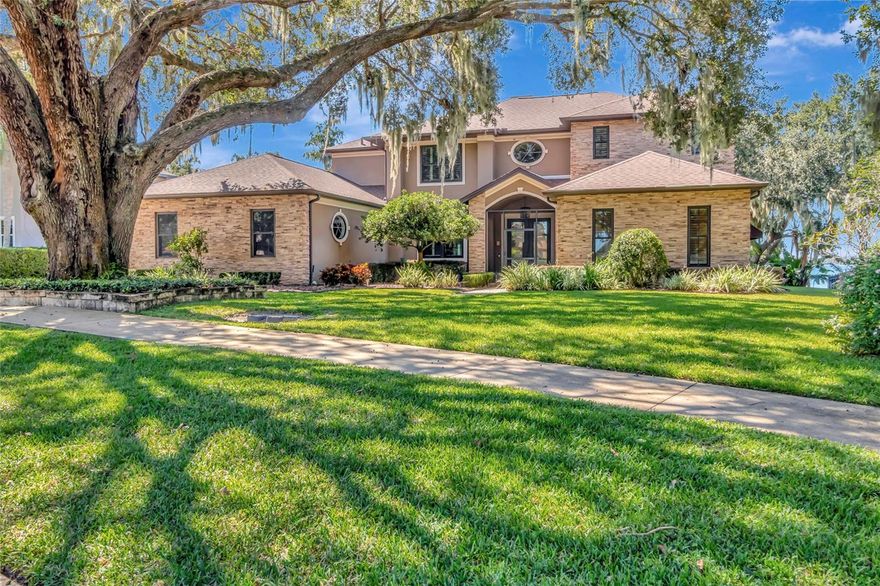 Welcome to your own piece of lakefront paradise in Clermont’s highly desirable Margaree Gardens neighborhood. From the moment you arrive, you’ll be drawn in by the excellent curb appeal, lush mature landscaping, and the majestic oak tree that graces the front yard—setting the tone for the beauty and serenity that continue throughout this home. Step inside, and you’ll immediately feel the warmth and comfort of this inviting four-bedroom, four-and-a-half-bath residence. The spacious floor plan is designed for both easy everyday living and effortless entertaining. A grand formal foyer welcomes you with natural light and leads to elegant spaces that flow seamlessly together. The formal dining room, highlighted by a cozy fireplace, is perfect for hosting gatherings, while the private office with custom sliding wood doors offers a quiet place to work or unwind. At the heart of the home is a beautifully appointed kitchen, featuring an oversized granite island, matching backsplash, and a layout that opens directly to the family room. With a double-sided fireplace, built-in entertainment center, and hardwood floors, this space feels both comfortable and refined. Toward the back of the home, a large multipurpose room provides plenty of flexibility for a game area, gym, or additional dining space—all while offering tranquil views of the lake. The primary suite, conveniently located on the main level, serves as a relaxing retreat with dual vanities, a Jacuzzi tub, a spacious walk-in shower, and generous closet space with closets on either side of long hallway. Upstairs, three large bedrooms each feature their own fully remodeled ensuite bathrooms (completed in 2025)—making it ideal for family and guests alike. Every detail of this home has been carefully maintained and thoughtfully upgraded. Notable improvements include a fully paid solar system with battery backup, mosquito misting system, automatic screen for the boat lift, gutter guards, custom bar, new carpet upstairs, new porcelain tile in the Florida/game room and primary suite, plantation shutters, pet friendly turf in backyard, new windows (installed in 2020), water softener system, and a 90-gallon energy-efficient hot water heater. The kitchen appliances are newer as well, with the refrigerator and dishwasher replaced just last year. Car enthusiasts and hobbyists will love the three-car garage plus an additional oversized fourth garage with soaring ceilings and epoxy flooring—complete with an outlet for an electric car charger. Step outside and discover what truly makes this property special. The expansive back deck leads down to a fully covered boat dock, perfect for fishing, entertaining, or evening cruises on the Clermont Chain of Lakes. A spacious covered porch overlooks the beautifully landscaped, fenced backyard that’s ideal for family gatherings or simply relaxing in your private outdoor retreat. Perfectly situated within the City of Clermont, this home offers the best of both worlds: the peace and beauty of lakeside living just minutes from the charming shops, restaurants, and community events of downtown. From sunrise paddleboarding to evenings spent watching the sunset from your deck, this is a home that celebrates Florida living at its finest. Don’t miss the chance to make this one-of-a-kind lakefront retreat your own!