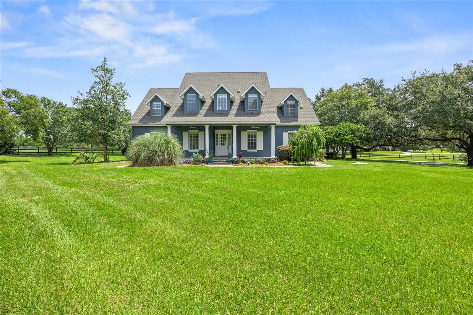 For the discerning equestrian, this turnkey property offers that rare combination of a manageable-sized horse farm, together with a spacious and well maintained home. This 5 BR/4.5 BA classic gabled home features a front porch with sweeping vistas. As you step inside you're greeted with wood-like tile flooring throughout, an expansive, airy flow with beautifully beamed ceilings, a stunning gas, double-sided stone fireplace and 3 sets of french doors to the fabulous pool area. The outdoor space is perfect for entertaining with it's covered patio, outdoor summer kitchen, outdoor shower and freshly sealed pavers that surround the 36'x18' pool. The kitchen has an updated warm and rustic feel with top of the line appliances, 2 copper sinks and island with seating. The main floor has the large primary with an area perfect for your home gym, office or seating area. The primary bathroom has two walk-in closets, a large walk-in shower, dual vanities and gorgeous claw foot soaking tub, as well as direct pool access. The second floor is breathtaking in it's size alone with a loft area to be used as a playroom or another entertainment area. With 4 large bedrooms, two with ensuite bathrooms and balconies, there is always room for guests. The property is completely fenced so your horses can appreciate the lush grass of 3 large paddocks that encompass the 3 stall center aisle block-built barn with tackroom and washrack. Conveniently located in the gated horse community of Post Horn and in the center of Marion County's horse country, sitting on 5+acres, with frontage on 475, it's an easy commute to town, hospitals, schools, the Florida Greenway and the Florida Horse Park. With a new roof in 2021 and 2 new HVACs in 2023, this gorgeous property is ready for you!