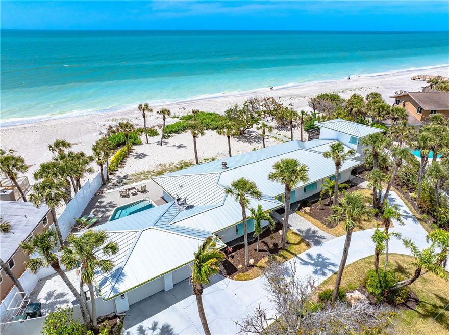 One or more photo(s) has been virtually staged. Timeless Gulf-Front Dream Home with Guest House. Experience coastal elegance in this extraordinary 4-bedroom beachside estate, perched high on nearly an acre with 150 feet of pristine private beachfront. Designed with light, space, and craftsmanship in mind, this home offers sweeping Gulf views and effortless indoor-outdoor living.
The gourmet kitchen is a chef’s delight, featuring quartz countertops, a large island, built-in desk, and professional-grade appliances. Entertain with ease in the spacious dining room and open-concept great room with a cozy fireplace and multiple seating areas for both comfort and sophistication. Bathrooms are adorned with beautiful Carrera marble, while the full-size laundry room offers abundant cabinetry and a utility sink. Natural hues and light-filled interiors provide a serene backdrop for everyday living.
Connected by a breezeway, the two-story guest house offers the same charm and quality as the main residence—perfect for guests or extended family.
Outside, enjoy a walk-in pool, swaying palms, and manicured tropical landscaping—all just steps from your secluded beach. Partially fenced for privacy, this is truly a rare and refined coastal retreat.