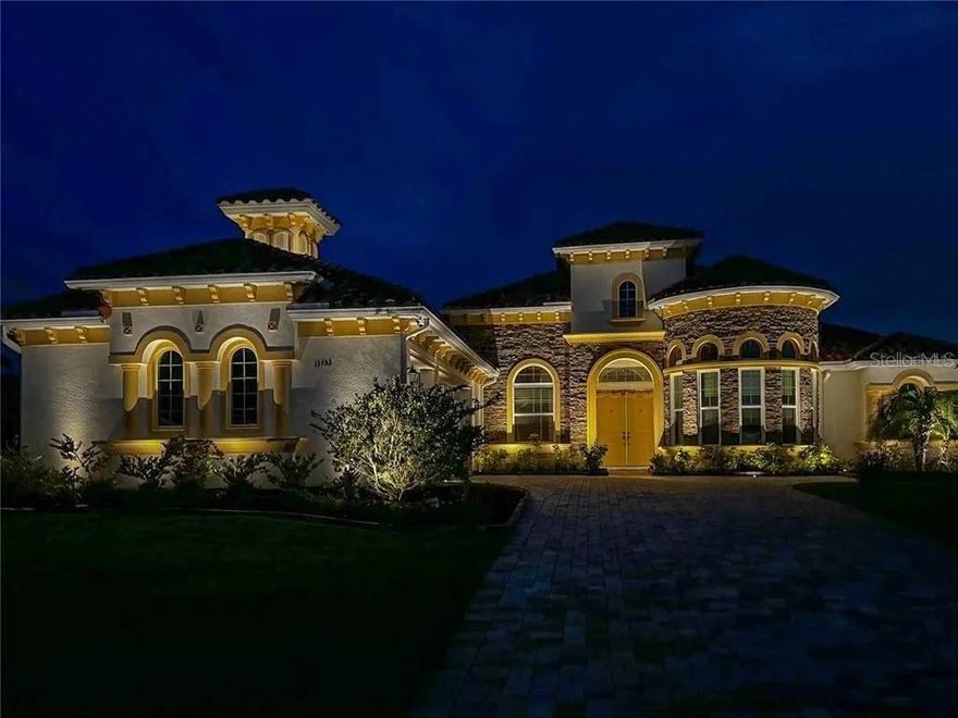 Step into a world of unparalleled luxury with this 2022-built custom estate, a one-of-a-kind sanctuary spanning 3,440 square feet on a sprawling 0.67-acre lot in the prestigious Lake Jovita Golf & Country Club subdivision of Dade City. From the moment you approach the 90-foot paver-lined entrance, the home’s striking architecture—crowned by a durable concrete tile roof and a grand 13-foot covered foyer—signals a residence of extraordinary caliber. Inside, the expansive floor plan is a masterclass in designer finishes, where 13-foot ceilings soar above ceramic tile floors and special-kind crystal chandeliers cast a radiant glow over the formal dining and living areas. The heart of the home is a gourmet chef’s dream, featuring custom high-end cabinetry, upgraded granite countertops, and a full suite of high-quality appliances—including a dedicated small freezer and a 250-gallon underground propane tank for precision gas cooking. The primary suite is a private retreat, offering dual "his and her" walk-in closets and a spa-inspired en-suite bathroom complete with high-pressure jets and a rain shower for ultimate relaxation. Each of the additional four bedrooms is thoughtfully designed with high-quality blinds; two guest rooms share a Jack-and-Jill bath with a rain shower, while another serves as a massive game room with side-by-side draw curtains for cinematic entertainment. A private office, featuring 8-foot French doors and abundant natural light, provides the perfect environment for a professional home base. Modern conveniences abound, including a well-appointed laundry room with extra storage, a water softener system, and a fully paid solar system that ensures energy efficiency without compromising on power. The seamless indoor-outdoor flow is anchored by four-panel sliding doors with remote motorized shades, leading to a travertine-finished lanai that defines the Florida lifestyle. Here, you’ll find a massive 36x23 ft saltwater pool and an 8-jet hot water spa—all controlled via a mobile automation system and illuminated by color-changing LED lights. The outdoor kitchen is equally impressive, boasting a full grill, gas burners, and custom granite countertops ideal for year-round gatherings. Extensive 34 LED outdoor lights transform the home into the community’s most stunning nighttime landmark, while the lush landscape, featuring seasonal fruit trees, is maintained by a cost-effective well-fed sprinkler system with rust prevention. Beyond your private gate, the Lake Jovita community offers a resort lifestyle with two award-winning 18-hole golf courses, a world-class clubhouse, and Har-Tru clay tennis courts. Your HOA fee even covers 1GB fiber optic streaming service, keeping you connected in this peaceful haven. Located just 20 minutes from North Tampa and an hour from Orlando, this home represents a rare opportunity to own a modern masterpiece in a neighborhood voted among the Top 100 Places to Live.