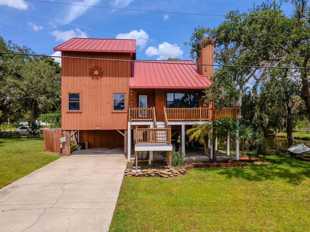 Tucked away on a spacious .31-acre corner lot with two deeded river access points, this elevated stilt home sits five feet above base flood elevation—remaining dry and damage-free through Florida’s recent hurricanes. With no HOA and a quiet neighborhood setting, it offers rare flexibility to live in, invest, or operate as an Airbnb in a scenic waterfront location. The new Trex wraparound deck (May 2024) is ideal for enjoying the wildlife that frequents the property—eagles, herons, fish, and crabs—or simply relaxing in the sun. The vaulted living room features a wood-burning fireplace and opens directly to the wraparound deck. The first-floor primary suite features dual closets and a large ensuite bath with a walk-in shower and soaking tub, while two additional bedrooms upstairs share a full bath. The open ground level offers flexible space for parking, storage, or creating a shaded hangout zone—perfect for tools, toys, or weekend projects. A tucked-away concrete slab behind the fence provides space to store a boat. Flood and termite policies are transferable, and the water heater was replaced in December 2024. The septic tank was drained, inspected, and serviced within the last year and had no issues. Whether you're looking for a peaceful primary residence, a smart investment, or an Airbnb-ready rental, this versatile home checks all the boxes. Add in proximity to boat ramps and all that Tampa provides, and you’ll see why this is a rare opportunity. Book your showing today before it’s gone!