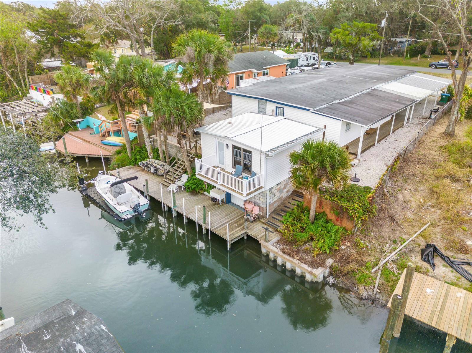 This impeccably maintained property blends the charm of a home with a stunning custom addition, all in pristine condition. Featuring five bedrooms, including one thoughtfully, this fully furnished, move-in-ready home is prepared for immediate use. Nestled along a canal with direct access to the Intracoastal Waterway, the property is a dream for water enthusiasts. It boasts a private boathouse, a 50-foot dock, brand-new decking, and a floating dock system with a mechanism for securing boats in shallow waters. Whether you enjoy boating, kayaking, paddleboarding, or fishing, this location offers endless opportunities for outdoor adventure.
The home has been freshly painted indoors and includes two central A/C units, one of which is brand-new. A new sewer hookup was installed last year, and the studio that overlooks the canal at the home’s level has been fully renovated with insulation, wood paneling, lighting, making it versatile for various uses.
Conveniently located just an hour from Orlando International Airport, the property is also close to New Smyrna Beach, Cape Canaveral, and the scenic Mosquito Lagoon, renowned for its exceptional fishing. Whether you’re seeking a peaceful waterfront residence or an incredible rental investment, this canalfront oasis offers a unique combination of relaxation, adventure, and opportunity. Boat, Furniture and the floating dock are negotiable. More Pictures Coming Soon!!