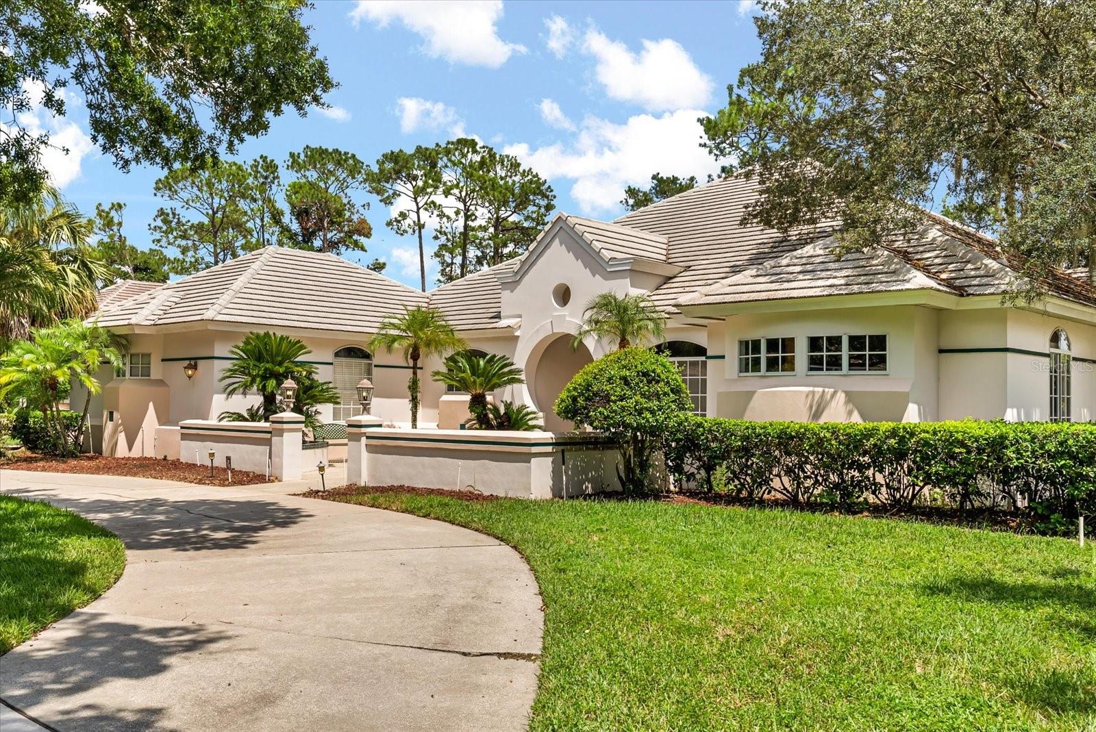 Welcome to Brentwood Club, a neighborhood of custom homes where this residence truly stands above the rest. Designed by renowned Orlando architects Charlan Brock and built by Tec Homes, the craftsmanship and attention to detail are evident at every turn.
Gracefully set on a private .41-acre lot with lush landscaping, the home sits within a quiet community of unique residences. A circular driveway leads to a spacious exterior courtyard, setting the tone for the inviting entrance. Inside, soaring ceilings, dramatic windows, a circular formal living room, and abundant natural light create a warm, open atmosphere.
The expansive Principal Suite serves as a serene sanctuary with beautiful arched windows, complemented by three additional bedrooms and two full baths—one of which could easily function as a second Principal Suite. With four bedrooms and three full baths overall, the floor plan is both functional and flexible, ideal for everyday living as well as entertaining. Architectural elements repeat throughout the home, creating harmony and a seamless flow from one space to the next, indoors and out. Transom windows above room thresholds add light and visual interest.
Outdoors, the pool and spa area is partially enclosed by a thoughtfully designed property wall, creating a courtyard-like atmosphere that balances openness with privacy. To the side, an expansive area offers endless possibilities—whether hosting large gatherings or envisioning a pool house, in-law suite, or art studio.
All of this is just moments from Orlando’s most dynamic employers, including Walt Disney World, Universal Orlando, Lockheed Martin, and AdventHealth. Just minutes away, Restaurant Row offers an impressive range of dining—from handmade pastas at Christini’s to fresh seafood at Ocean Prime and craft cocktails at Rocco’s Tacos. Golfers will love the proximity to Arnold Palmer’s Bay Hill Club & Lodge, home of the annual Invitational, while nature enthusiasts can enjoy peaceful walks and water adventures along the scenic Butler Chain of Lakes.
Here, luxury and convenience go hand in hand—mornings on the green, afternoons on the water, and evenings filled with unforgettable flavors. It’s a lifestyle that blends recreation, relaxation, and sophistication in one of Orlando’s most desirable settings.