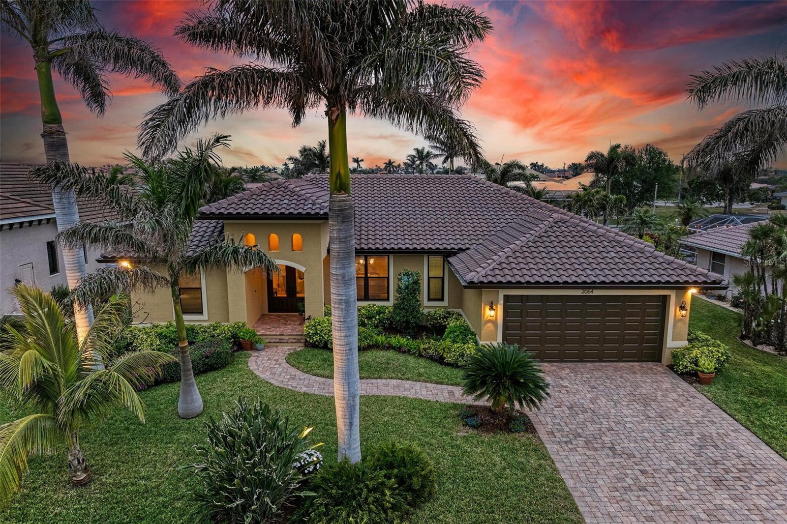 WATERFRONT LUXURY AWAITS at this gorgeous 2013 built custom POOL HOME with incredible and unique features! This 3-bedroom, 3 full bath –2,205 sqft air conditioned / 3,260 sqft total home on an 85’ x 120’ oversized lot has an oversized two car garage with a large climate-controlled storage room, a NEW cement tile roof with double underlayment, new soffit and 7” gutters, a refurbished cage, new garage epoxy flooring, all completed in 2024. Inside, enjoy two guest bedrooms, each with their own bathroom on the left side of the home, an open concept design including the dining room, spacious great room, kitchen and dinette all open to the outdoors via six - 8’ tall sliders that create indoor/outdoor spaces with wonderful views of the water and pool, a beautiful primary suite with dual walk-in closets and an en-suite bathroom with separate tub and walk-in shower, and upgraded dual vanities. Additional features include a large inside laundry room with extra storage, a commercial grade flagpole, upgraded landscaping, audio speakers in main living area and outside porches, Impact windows and Storm Smart hurricane shutters for lanai, 20” porcelain tile flooring throughout, tongue and groove ceilings in main living area and outside porches, a huge walk-in pantry large enough for a deep freeze off the beautiful gourmet kitchen, an amazing outdoor kitchen and bar with propane grill and additional two burner cooktop, a heated saltwater gunite pool that is 7’ deep, landscape decorative lighting, a fabulous 35' concrete dock with 20,000 lb lift, shore power, and 2 hose spigots. This home also is GENERATOR READY with a plugin adaptor for home power. Nearby to great shopping, restaurants, marinas, golf, parks and more, you will not want to miss this! BE SURE TO CLICK THE FULL VIRTUAL TOUR LINKS FOR DETAILS!