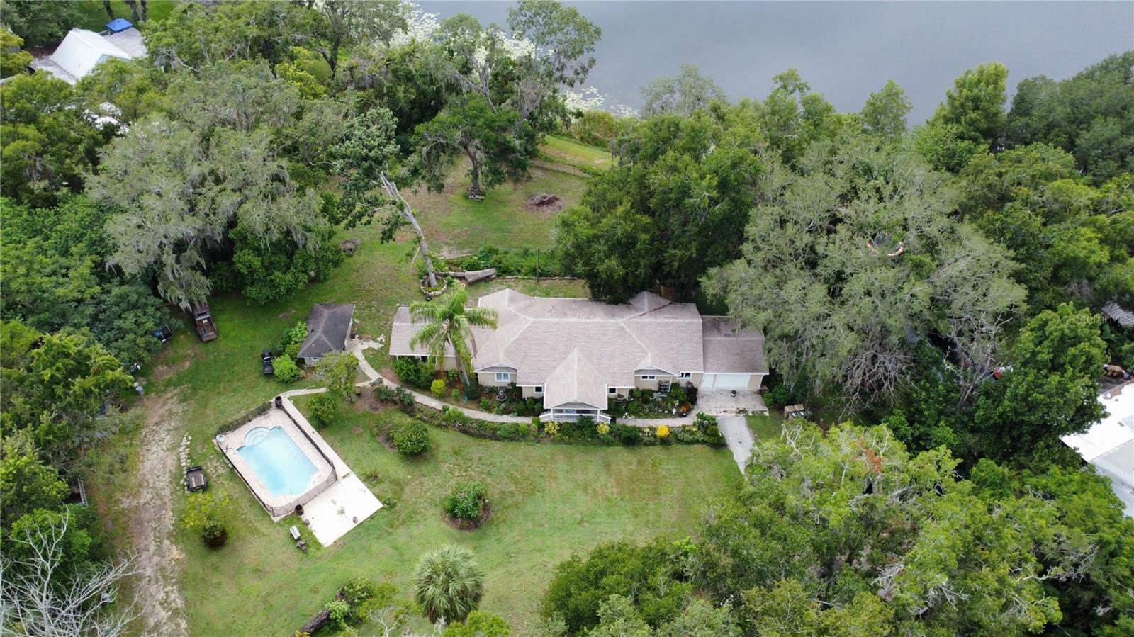 STOP THE CAR! Escape to the peace of this beautiful WATERFRONT home. Experience the joy of a country lifestyle while living in the city, within distance to all major shopping, roads, and restaurants. As a BONUS, there is NO HOA!!! The property spans 3.64 acres, with two acres being high and dry, providing ample room for privacy and play, and is fenced around the entire perimeter of the house. Fabulous custom-made saltwater pool with a gas heater; there is plenty of room to add a cottage, as an additional well and septic are available. Don't let age fool you; this home has been completely remodeled with upgraded laminate flooring, porcelain tile, a renovated kitchen and baths, upgraded electrical, light fixtures, and fans. The kitchen features stainless steel appliances, tile backsplash, granite countertops, and modern cabinets. It is designed for anyone who enjoys cooking and entertaining simultaneously. The property features a breakfast area, a large utility room off the kitchen, and a spacious outdoor deck for outdoor enjoyment. As you enter the home, you will love the large formal living/ dining room, which is filled with natural light. The family room has breathtaking views of the spring-fed lake. The garage has been converted into a beautiful whole apartment, and the basement also features an apartment. The roof, AC unit, and water heater were installed in 2017. Grab your fishing pole or launch your kayak for hours of lakefront fun. If you're looking for Florida living with a pool, lake access, plenty of space, and proximity to everything, this is it! Look no more! Welcome to the most peaceful setting for your dream home!!