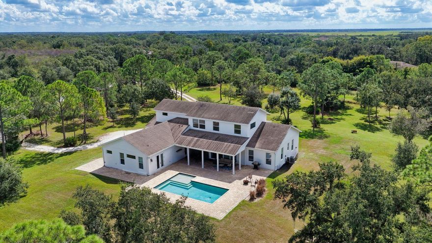 Welcome to this 2016 custom-built modern farmhouse set on over 5 peaceful acres, offering the perfect blend of refined design and relaxed country living. Surrounded by natural beauty and frequent wildlife sightings, this private Sarasota retreat features 4 bedrooms, 4 baths, and thoughtfully crafted spaces throughout.

A grand entry through Therma Tru double doors leads to an inviting foyer and a spacious great room with soaring ceilings and abundant natural light. The chef’s kitchen is a standout with gas cooktop, pot filler, oversized quartz island, custom B&B shaker cabinetry, reverse osmosis system, pantry, and built-in features. The dining area centers around a beautiful gas stone fireplace for warm, elegant gatherings. A dedicated office/media room with double doors and a versatile loft offer ideal spaces for work, entertainment, or relaxation.

The primary suite includes French doors to the pool area, a luxurious bath with double vanity, and a private water closet. This split plan provides two additional bedrooms and a full bath downstairs, while the upstairs includes a spacious loft and a large fourth bedroom/bonus room for added privacy and flexibility. A well-appointed laundry room and full pool bath add convenience. Stylish polished concrete floors run throughout the home, blending modern design with rustic warmth.

Property features include hurricane-impact windows and sliders, a 10-foot-plus two-car garage suitable for a lift, three AC units, whole-house generator, water softener, tankless water heater (NR980D), operational well, septic system with 1,350-gallon tank and 84 sq. ft. drain field, and a 500-gallon buried propane tank.

Outdoor living is exceptional with a sparkling saltwater pool, expansive paver deck, covered patio, and plumbing in place for an outdoor kitchen. The acreage offers ample room for an additional structure or barn, making it suitable for a homestead, equestrian use, or quiet nature retreat. Enjoy peaceful mornings and sunsets on the charming covered front porch, and experience the serenity of this one-of-a-kind Sarasota property.