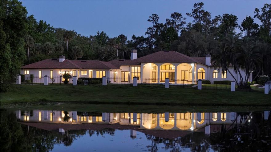 Set at the end of a quiet cul-de-sac and backing to the protected beauty of Wekiwa Springs State Park, this extraordinary waterfront estate offers a rare blend of privacy, scale, and natural serenity within the coveted Markham Woods Corridor. Fully fenced and positioned to capture sweeping conservation and water views, the setting alone places this residence in a category few can match.

Impressive private gates and a brick paver circular drive introduces a dramatic arrival, where a grand porte cochere and expansive six-car motor court set the tone. Inside, the home has been completely reimagined through a comprehensive renovation, unveiling soaring ceilings, walls of glass, and abundant natural light. A striking five-foot by eight-foot pivot door opens to a refined foyer with porcelain tile and white oak flooring, immediately drawing the eye to the shimmering pool and tranquil pond beyond.

Designed for both grand entertaining and effortless living, the main areas unfold in a seamless open-concept layout. With 14-foot ceilings and expansive living, dining, family, and kitchen spaces flowing together, the home offers impressive volume and connectivity. Anchoring the heart of the home, a dramatic double-sided wood-burning fireplace creates a warm focal point between the kitchen and family room. The chef’s kitchen is a true showpiece, featuring Wolf appliances, built-in refrigeration, and an oversized island with seating for six, finished with elegant waterfall-edge countertops.

Outdoor living is equally captivating. A vast travertine lanai transitions to an oversized resort-style pool, all set against a breathtaking backdrop of water and untouched conservation. Nearly every room is oriented to capture these remarkable views, creating a constant connection to the landscape.

The primary suite is a sanctuary of grand scale, offering serene water and wooded vistas. Its bespoke bath features leather-finished stone countertops, dual vanities, a soaking tub, and picture windows framing the natural setting. A spa-inspired steam shower with multiple shower heads and a built-in bench completes the experience. Dual custom walk-in closets elevate functionality, one with a center island and scenic window, the other concealing a hidden safe room.

Versatility defines the additional spaces. A dedicated office with walk-in closet and direct bath access can serve as an additional bedroom. A generously sized bonus room is ideal for a home theater, library, or lounge, while a separate gym with luxury vinyl flooring can easily function as a second office. A thoughtfully positioned flex space between the main residence and guest quarters opens to the lanai and pool bath, ideal for a cabana lounge or wellness retreat.

The guest quarters is a residence unto itself, featuring two bedrooms, two baths, a spacious great room, full kitchen with center island, separate motor court access, and its own laundry, offering exceptional accommodations for guests or multigenerational living.

Homes of this caliber rarely come to market. The extensive renovation, remarkable scale, and exceptional attention to detail are perfectly paired with Seminole County’s most desirable locations. Zoned for top-rated schools and ideally positioned near Longwood and Lake Mary, with convenient access to major highways, regional hospitals, airports, beaches, and Central Florida’s world-renowned attractions, this is a legacy property that defines elevated Florida living.