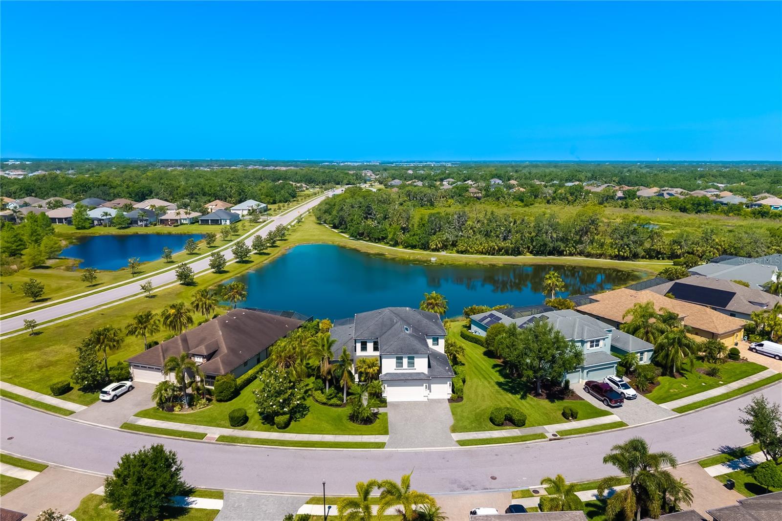 Premium WATERVIEW AND NATURE PRESERVE VIEW LOT in highly desirable Greyhawk Landing home 826 Honeyflower Loop, a masterpiece of elegance and comfort, nestled on a private, picturesque lake and nature preserve lot in the exclusive gated, multigenerational enclave of Greyhawk Landing. This exquisitely appointed 4-bedroom, 4.5-bath with whole house SURGE PROTECTOR, IMPACT WINDOWS AND DOORS, EV charger with high voltage modification, offers the coveted Sawgrass floor plan with over 3,700 sq ft of refined living space. Two second floor bonus rooms, one entertainment room and a game room perfectly designed for both everyday comfort and entertainment for everyone to enjoy. Step inside and discover an open concept layout with soaring coffered ceilings, designer lighting, custom millwork, and a great room anchored by a gourmet chef’s kitchen, formal dining with custom built-ins and ambient rope lighting, abundant natural light. Refined finishes throughout seamlessly blending architecture elegance with high-end finishes, flooring with larger ceramic tile, engineered hardwood throughout, no carpet. Kitchen is outfitted with premium stainless-steel appliances, Thermador Gas Range, Bosch Dishwasher, wood cabinetry, butler’s pantry, pot drawers, granite countertops, backsplash, spacious island, and is as functional as it is beautiful, ideal for gathering. The lavish first-floor primary suite is a true retreat with elegant ceiling details, dual walk-in closets with custom built-ins, and direct views of the resort-style pool and spa. Indulge in the spa-like primary ensuite bath with a soaking tub, frameless Roman shower, dual vanities, and dedicated makeup station. Three additional bedrooms and two baths upstairs, fourth bath outside pool bath, provide space and flexibility for guests, in-laws or a home office. Upstairs, enjoy a loft bonus entertainment room and a separate private game room with wet bar, ideal for a billiards lounge, or home theater. Step outside to your private tropical oasis, featuring a sparkling heated pool, elevated spa, an expansive screened lanai, textured marble lanai set against serene water views and preserve views is the perfect backdrop that captures the essence of Luxury Florida living and nature. Residents of Grayhawk Landing have access to exceptional community amenities, $70 a year HOA: 24-Hour Gated Community, Social Events/Clubs, Gym, Fitness Facility, Tennis, Pickleball, Basketball Courts, Playgrounds, Fishing Pier, Baseball, Soccer Fields, Lagoon-style Pool, Spas. Ideally situated near Lakewood Ranch in the heart of Sarasota/Bradenton, I-75, proximity to world-renowned Siesta Key Beach, Anna Maria Island and Longboat Key, premier shopping, UTC Mall and St. Armand’s Circle, and dining, championship golf, boating, top-rated schools, and more. All set against the breathtaking backdrop of scenic preserved woodlands and sparkling lakes with over 5 miles of walking trails that weave throughout the community. This is more than a home, it’s a lifestyle. This home presents an exceptional opportunity, schedule your private showing today 826 Honeyflower, Bradenton, FL 34212 and start discovering why Greyhawk Landing is the place to be.