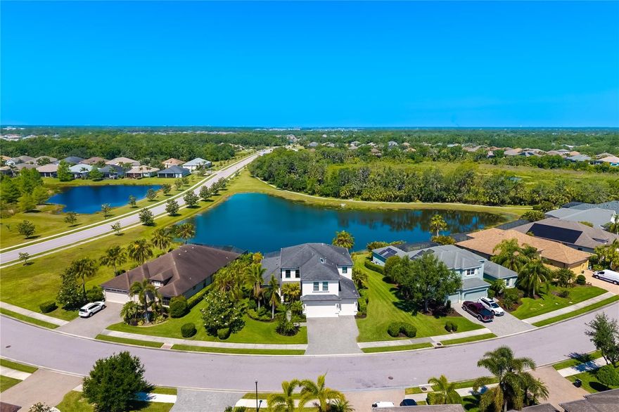 Premium water and nature preserve views set the stage for this stunning 4-bedroom, 4.5-bath, with 2 upstairs bonus rooms Sawgrass model in the gated community of Greyhawk Landing, where fencing is allowed. With over 3,700 sq ft of living space, this home offers impact windows/doors, EV charger, whole-house surge protector, and refined finishes including engineered hardwood and designer lighting. The gourmet kitchen features a Thermador gas range, Bosch dishwasher, granite countertops, butler’s pantry, and large island, opening to a spacious great room and formal dining. The first-floor primary suite boasts custom walk-in closets, spa-like bath with soaking tub and Roman shower, and views of the resort-style pool and spa. Upstairs are three guest bedrooms, two full baths, plus dual bonus rooms—ideal for media, game room, or home office, or potential 5 bedroom, in-law suite. Outdoor living shines with a heated pool, elevated spa, expansive screened lanai, and marble decking, all overlooking serene lake and preserve views. Enjoy Greyhawk Landing’s resort amenities for just $70/year, with pools, clubhouse, fitness, tennis, pickleball, sports courts, playgrounds, and miles of trails. Convenient to Lakewood Ranch, I-75, medical facilities, schools, shopping, dining, golf, and Gulf Coast beaches.