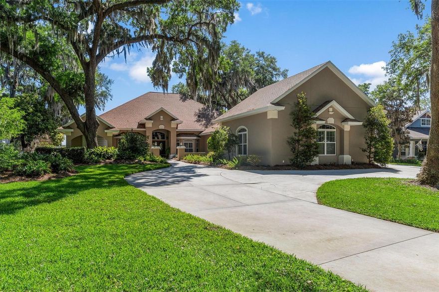 Wingspread POOL home on the LAKE! Welcome to one of Wingspread’s most impressive waterfront residences—custom built for its original owner and thoughtfully designed to capture both beauty and function. Tucked away on a peaceful 1.52 acre lot in a sought-after neighborhood, this home offers exceptional curb appeal with a long, picturesque circular driveway providing plenty of parking while maintaining a peaceful, set-back feel. Inside, you’ll find nearly 3,900 square feet of living space with a layout that flows effortlessly from room to room. The home features three spacious bedrooms, each with its own en-suite bath, along with a convenient half bath for guests. A formal living room and dining room provide elegant entertaining spaces, while the heart of the home opens into a warm and inviting family room with a fireplace, seamlessly connected to the kitchen and casual dining area. The kitchen is beautifully finished with custom cabinetry, pull-out storage, a center island, breakfast bar, built-in desk area, and top-of-the-line appliances—designed for both everyday living and hosting. Expansive sliding glass doors recede, blending indoor and outdoor living and drawing your eye to the stunning screened pool and lanai. With over 860 square feet of covered outdoor space, this area is ideal for entertaining, complete with paver decking, an outdoor counter entertaining area with cabinetry, refrigerator, wet bar, and peaceful lake views. The primary suite also enjoys direct access to the pool and offers generous closet space, a luxurious bath with a walk-in shower, garden tub, dual vanities, and a dedicated sit-down vanity area. Additional features include stunning wood flooring throughout, plantation shutters, and a private office or den perfect for working from home. For those needing exceptional storage or garage space, this property truly stands apart—offering approximately 1,566 square feet of garage space with soaring 14-foot ceilings... ideal for an RV or boat. A full staircase leads to a 400+ square foot second-floor storage room, providing even more storage. Outdoors, the property continues to impress with a beautifully maintained yard, a 14-zone irrigation system fed by a separate well, and a fenced area for pets. A private boat dock completes the waterfront lifestyle, making it easy to enjoy everything this serene lakefront setting has to offer. This is a rare opportunity to own a truly custom, well-designed waterfront home in one of Fruitland Park’s most desirable communities.