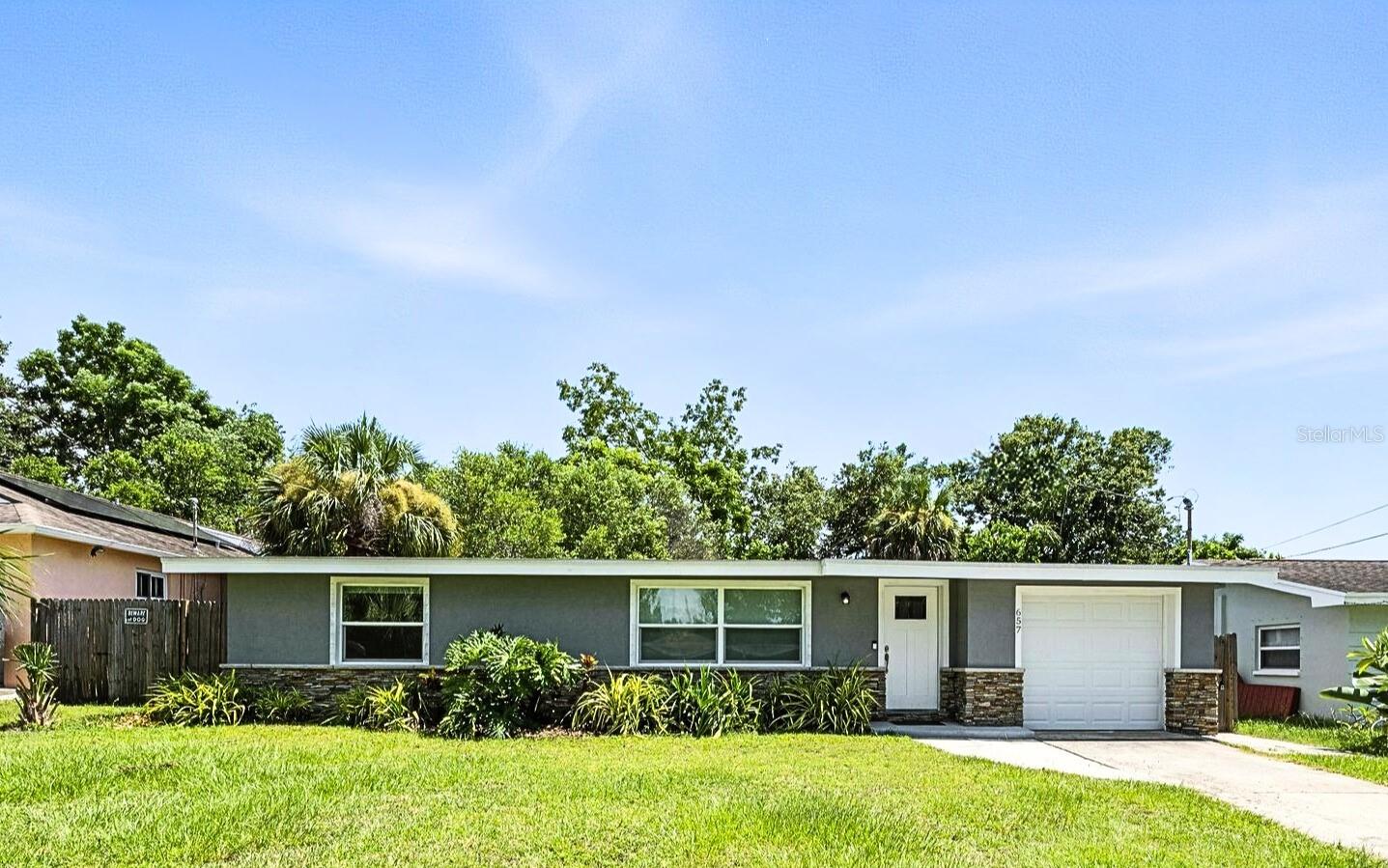 Settled in Dunedin’s beloved golf-cart district, this fully re-imagined 3-bed | 2-bath home with a stylish office nook puts the entire downtown scene at your fingertips—award-winning eateries, craft breweries, indie coffee spots, the Pinellas Trail, Weaver Park, and the City Pier are all a quick stroll or cart ride away. Located in no Flood Zone. Inside, everything feels brand-new: roof, HVAC, windows, electrical, plumbing, insulation, and level-5 drywall—wrapped in wide-plank flooring and drenched in natural light. The airy great room pivots around a show-stopper kitchen featuring a leathered-granite two-tier island—counter height below and a raised bar for tall stools, custom cabinetry, sleek vent-hood range, and an eye-catching designer backsplash. It’s the perfect stage for gathering friends and family.
Just beyond the work-from-home nook, the private primary retreat serves up a a gorgeous view to the grand fenced-in patio and a bath clad in luxe tile. Two additional bedrooms share a chic hall bath on their own wing, offering ideal separation for guests or little ones. Slide the glass doors open to a backyard designed for Florida living: a screened-in rear porch leads to an expansive paver patio and a plush astro-turf lawn big enough for your future pool. The yard is also dialed-in for easy maintenance with a front-yard sprinkler system and drip-line irrigation for the back garden beds, controlled via smartphone app—a true low-maintenance haven for grilling, lounging, or unforgettable starlit evenings around the fire pit.