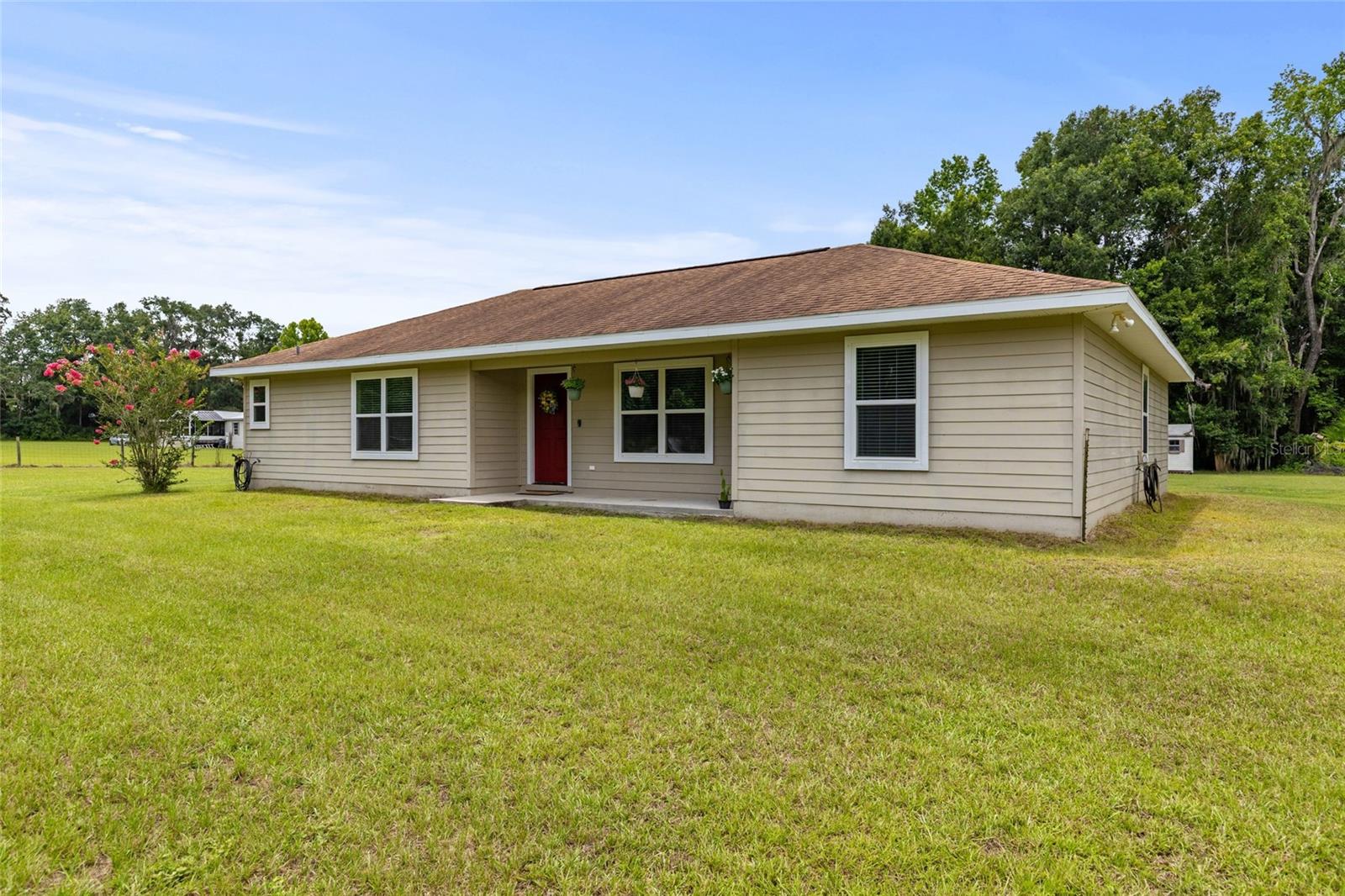 Welcome to this charming, like-new 4-bedroom, 2-bathroom, 1,756 sqft home built in 2016 sitting on an amazing 5.5 acres of land! As you approach the home, you will appreciate the surrounding peace and quiet, the low maintenance front yard, and the durable hardiboard siding on the house. As you step into the home, you will be greeted by an open concept living and dining area with vaulted ceilings and wood-look tile flooring throughout the house. The open concept layout of the space makes it a breeze to host get-togethers for special occasions or holidays. As you move through the home, you will find the kitchen on the left. It has wooden cabinets, stainless steel appliances, a pantry, and it also provides access to your very spacious laundry room. The primary bedroom is located on the left side of the house, overlooking the front yard. It has a large walk-in closet and an en-suite bathroom with a tiled tub shower combo. The secondary bedrooms are located on the right side of the house with built-in closets and a shared bathroom which also has a tiled shower tub combo. Step outside to your tranquil oasis and let your imagination create your dream backyard - add a pool, bring your horses, or just enjoy time with friends and family around a BBQ. With a large 30x30 metal RV port and a shed, there's plenty of space for all your tools and outdoor toys. Discover the perfect blend of open pasture and serene woodland on this stunning 5.5 acre property, offering a rare opportunity to enjoy the best of both worlds. Pack up your canoe and visit one of the nearby springs all while being a short drive from Gainesville as I75 is just a few minutes away. Don't miss out on this amazing opportunity and schedule an appointment today!