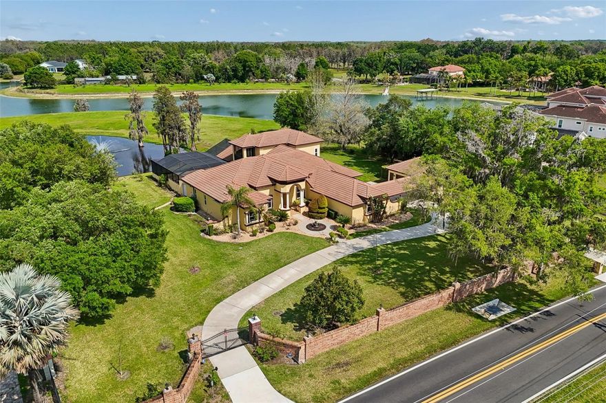 This exquisite lakefront estate masterfully blends elegant living with the tranquility of nature. Spanning almost three acres, with over 200 feet of pristine Lake Breckenridge frontage, the property offers kayaking, jet skiing and boating. The electronically gated entrance introduces a meticulously landscaped realm, featuring a serene pond with a captivating, lighted fountain and abundant space for bespoke additions like a private dock or fun sport courts. Within, discover a residence of refined living that exemplifies the current design preference for modern Tuscan architecture, a style that balances the warm finishes of rustic charm with contemporary sophistication. Interior finishes include crown molding, attractive engineered wood flooring, and large-format, stone-look tile. The gourmet kitchen, a culinary enthusiast's delight, is appointed with lustrous quartz countertops and backsplash, custom rich wood cabinetry with integrated pullouts, an expansive center island, a dedicated wine bar, high-end appliances, and a gas cooktop. All four generously proportioned bedrooms are thoughtfully on the main level. Secondary bedrooms offer charming window seats, while a dedicated children’s lounge provides integrated homework centers. A versatile first-floor bonus room, commanding breathtaking lake views, presents the opportunity for a fifth bedroom or an independent in-law suite complete with a private entry, sitting room and en-suite bath. The lavish main primary suite features a private sitting room with panoramic views of the pond and lake, alongside a spa-inspired bath boasting a sumptuous soaking tub, dual vanities, and an expansive walk-in closet with custom built-ins and a central island dresser. A distinguished home office or library offers bespoke wood built-ins and rich wood flooring. Ascend to the upper level to an entertainer's dream, featuring a billiards room with a wet bar, refrigerator and microwave. Adjacent, a state-of-the-art media/theater room offers an immersive experience with a large screen, premium media equipment and stadium seating. A screened upstairs balcony provides an idyllic setting for stargazing or serene contemplation of the picturesque pond and lake. The outdoor sanctuary redefines resort-style living with an expansive 3,000-square-foot lanai designed for grand entertaining. It features a summer kitchen with a grill, refrigerator, and outdoor gas fireplace, an 8-foot-deep heated pool with a luxurious Pebble-Tec finish and heated spa. Further enhancing the grounds with full-property sprinkler irrigation and professional landscaping with LED lighting. Automotive enthusiasts will appreciate the six-car garage capacity offering extended-size garage doors and a 50-amp electric vehicle charger. For paramount security and efficiency, the estate is equipped with impact-resistant PGT and Simonton doors and windows, engineered to withstand winds of up to 200 mph. A whole-house 38-kilowatt Generac generator, powered by a 1,000-gallon buried propane tank, ensures uninterrupted comfort. Energy efficiency is further optimized by 80 LG solar panels and LED lighting throughout the interior. Advanced technology and security provisions include a custom 13-camera video surveillance system with mobile access, a comprehensive whole-house sound system, and sophisticated water purification and softening systems. Don’t miss out on this captivating residence.
