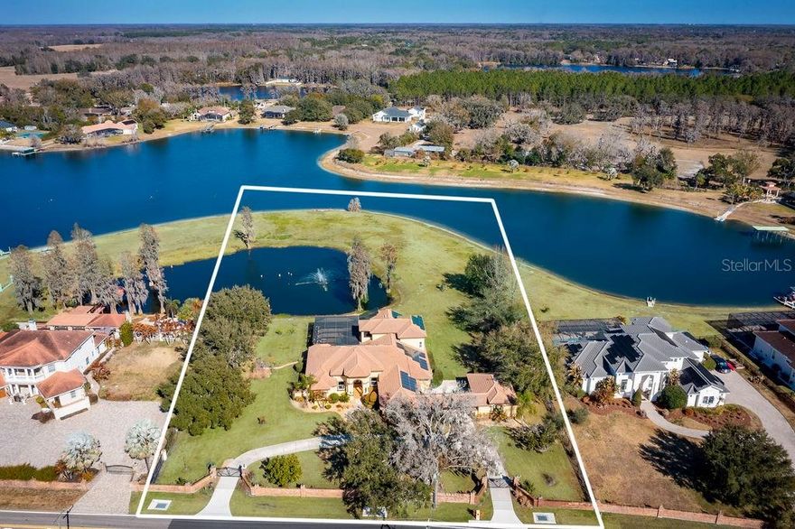 This exquisite lakefront estate masterfully blends elegant living with the tranquility of nature. Spanning almost three acres, with over 200 feet of pristine Lake Breckenridge frontage, the property offers kayaking, jet skiing and boating. The electronically gated entrance introduces a meticulously landscaped realm, featuring a serene pond with a captivating, lighted fountain and abundant space for bespoke additions like a private dock or fun sport courts. Within, discover a residence of refined living that exemplifies the current design preference for modern Tuscan architecture, a style that balances the warm finishes of rustic charm with contemporary sophistication. Interior finishes include crown molding, attractive engineered wood flooring, and large-format, stone-look tile. The gourmet kitchen, a culinary enthusiast's delight, is appointed with lustrous quartz countertops and backsplash, custom rich wood cabinetry with integrated pullouts, an expansive center island, a dedicated wine bar, high-end appliances, and a gas cooktop. All four generously proportioned bedrooms are thoughtfully on the main level. Secondary bedrooms offer charming window seats, while a dedicated children’s lounge provides integrated homework centers. A versatile first-floor bonus room, commanding breathtaking lake views, presents the opportunity for a fifth bedroom or an independent in-law suite complete with a private entry, sitting room and en-suite bath. The lavish main primary suite features a private sitting room with panoramic views of the pond and lake, alongside a spa-inspired bath boasting a sumptuous soaking tub, dual vanities, and an expansive walk-in closet with custom built-ins and a central island dresser. A distinguished home office or library offers bespoke wood built-ins and rich wood flooring. Ascend to the upper level to an entertainer's dream, featuring a billiards room with a wet bar, refrigerator and microwave. Adjacent, a state-of-the-art media/theater room offers an immersive experience with a large screen, premium media equipment and stadium seating. A screened upstairs balcony provides an idyllic setting for stargazing or serene contemplation of the picturesque pond and lake. The outdoor sanctuary redefines resort-style living with an expansive 3,000-square-foot lanai designed for grand entertaining. It features a summer kitchen with a grill, refrigerator, and outdoor gas fireplace, an 8-foot-deep heated pool with a luxurious Pebble-Tec finish and heated spa. Further enhancing the grounds with full-property sprinkler irrigation and professional landscaping with LED lighting. Automotive enthusiasts will appreciate the six-car garage capacity offering extended-size garage doors and a 50-amp electric vehicle charger. For paramount security and efficiency, the estate is equipped with impact-resistant PGT and Simonton doors and windows, engineered to withstand winds of up to 200 mph. A whole-house 38-kilowatt Generac generator, powered by a 1,000-gallon buried propane tank, ensures uninterrupted comfort. Energy efficiency is further optimized by 80 LG solar panels and LED lighting throughout the interior. Advanced technology and security provisions include a custom 13-camera video surveillance system with mobile access, a comprehensive whole-house sound system, and sophisticated water purification and softening systems. Don’t miss out on this captivating residence.