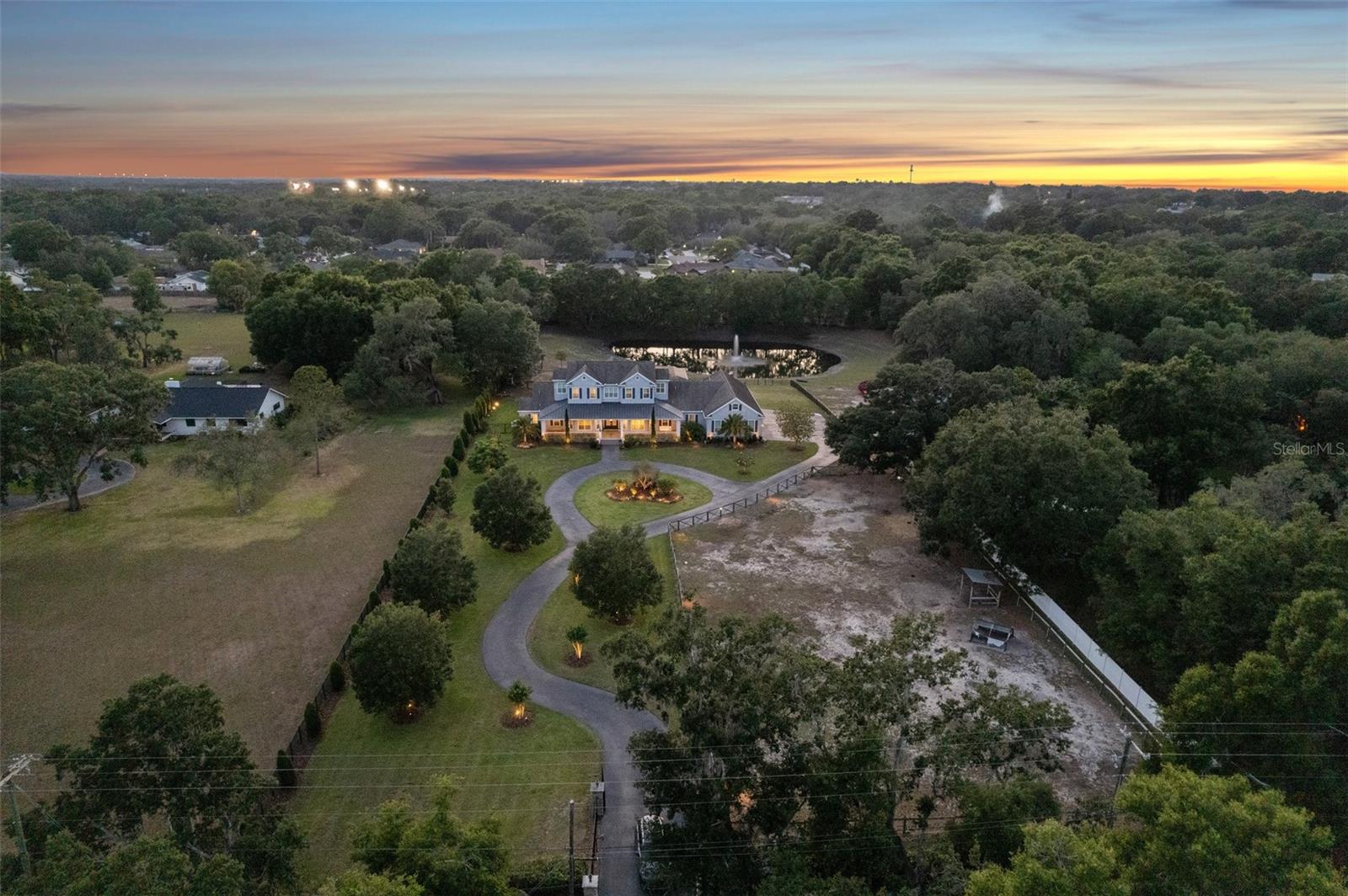 STUNNING LUXURY FARMHOUSE ESTATE feels like it’s straight out of the pages of Southern Living Magazine with its elegant modern design and picturesque surroundings. It is nestled on 4.2 fenced acres overlooking its own private, spring-fed pond and barn, and is conveniently located ONLY 15 miles from Tampa!! Escape to your own majestic peaceful paradise; this one has it all!! it doesn’t get much better than this!! You’ll enter through your private electric gate and drive up the winding driveway to this extraordinary and impressive 6,300 sq ft custom home (9,822 sq ft total) offering 5 bedrooms + 6 full bathrooms + an office/gym + formal sitting room + a theater room and game room with wet bar + an expansive oversized 6-car attached garage + an unrivaled outdoor living space with private resort-style, solar-heated pool with sun-shelf + a large covered impressive outdoor kitchen and lanai PERFECT for entertaining your family & friends! Whole home generator guarantees you are never without power. The charming barn is 1,800 sq ft and offers 6 stalls + a center aisle + feed room + tack room + wash/dressing station + its own half bath + covered front porch! Your new home offers an OPEN FLOOR PLAN with high ceilings making it light, bright and spacious! You have upgrades everywhere including crown molding in every room, plantation shutters, real wood cabinets, quartz and granite countertops throughout the entire home. All the bathrooms have ceramic tiled floors and showers with glass doors. The main living spaces have engineered hardwood floors. The spacious island-style chef’s gourmet kitchen has been recently remodeled and is the heart of this home; it is open to the large great room and dining room all with large glass doors offering views of your inviting pool, pond, and pastures!! The luxury kitchen is expansive with complementing rooms to include a large walk-in pantry + a large butler’s pantry with an extra refrigerator + a dry bar/coffee bar area + an ENVIOUS laundry room with dual washers and dryers + the home also offers a “Costco Room” to store all the items your family needs! You have more storage area in this home than you could ever wish for! All of these rooms have recently been remodeled with gorgeous modern Quartz countertops and backsplashes and have real wood cabinets! The kitchen offers all stainless steel luxury appliances to include 2 dishwashers, built-in double ovens, a Wolf gas cooktop, pot-filler, wine fridge, and ice-maker. The kitchen also has a large breakfast bar + additional seating at the island. 4 of the bedrooms have their own ensuite bathroom (what everyone wishes for) + walk-in closet with custom closet organizers!! The master bedroom is downstairs and large enough to boast its own cozy living room with a modern stone fireplace and private door to the outside lanai with outdoor living room! The master ensuite bathroom offers dual vanities/sinks with a large jetted tub, spacious walk-in shower, large walk-in closets, door to dog run! Additional downstairs bedroom with ensuite bathroom can be used as an MIL suite. Have a little fun fishing & canoeing, or walk outside down your paver path with a glass of wine to relax and unwind around your fire-pit overlooking your illuminated fountain! NO HOA! Bring the boat, RV, horses, pets, bring it all! Located close to everything...yet tucked away w/privacy & peacefulness! Call today to schedule your private showing of this unforgettable "straight-out-of-magazine" home!! Room Feature: Linen Closet In Bath (Primary Bathroom).