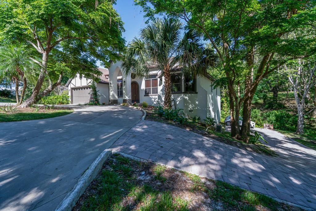 You don't want to miss this one-of-a-kind Mount Dora dream home! This totally unique and spacious custom home in Mount Dora's Historic District sits on a private .35-acre lot and is just a quick stroll to downtown Mount Dora with its unique shops, numerous festivals and award winning restaurants. WALKING DISTANCE! You will never have to drive again! This luxurious Spanish Tudor home features 5 or 6 bedrooms, 4 baths (3 ensuite), and 4,500 sq ft of beautiful living space under air. Outdoor space includes 2 huge screened porches, one on each level, overlooking a tropical wooded lot with a rear fenced yard, perfect for a pet. The lower level boasts a 26 x 23 game room, a FLEX ROOM that can be a 6th bedroom, theater or hurricane "safe" room, with concrete block walls surrounding it, and 2 master suites. Both levels have high ceilings (10' and 12'), beautiful hardwood floors upstairs, luxury vinyl downstairs, Calcutta quartz countertops, a circular driveway with 2 car garage, 2 office areas, and a 1 bedroom/1 bath guest suite with kitchenette on the lower level with a separate entrance, driveway & parking. The lower level is a perfect area for teens, guests, and extended family. It is a lockout from the upper level and feels like its own private 2200sf residence! The house is a solid 2 story concrete block construction which is unique to find in a single family residence today. Two A/C units and plenty of parking make this a very comfortable and flexible home with a GREAT location you won't want to miss!