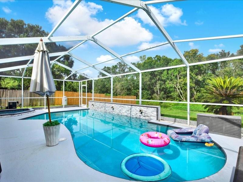 STUNNING POOL/SPA ON CANAL & PRESERVATION! No CDD & SUPER LOW HOA! This 3-bedroom, 2-bathroom, POOL and SPA home with a 2-car garage offers the perfect blend of comfort, functionality, and Florida lifestyle living. Step inside to a bright and airy open-concept layout with vaulted ceilings, skylight windows and a split floor plan designed for privacy and flow. The spacious great room features sliding glass doors and windows that frame beautiful views of the enclosed pool, in-ground spa and canal/preservation. Just off the great room, you’ll find a separate formal dining area—ideal for entertaining or hosting family gatherings. The kitchen is both stylish and functional, complete with wood cabinetry, granite countertops, and an eat-in dining nook with sliders leading directly to the lanai and pool. This home is perfectly designed for indoor/outdoor living. Your spacious primary suite is a true retreat, featuring a built-in dresser, a custom walk-in closet, upgraded dual vanity with granite countertops, and a fully tiled spa tub and shower. Two additional guest bedrooms are privately located on the opposite side of the home and share an updated full bath. Step out into your own backyard tropical oasis boasting a sparkling pool featuring an amazing stone accent wall with lighting and cascading fountains, an inground separate spa, and tranquil canal and preservation views. The sellers most favorite features are enjoying the natural landscape and watching the waterfowl including egrets, red shoulder hawks, ducks, sandhills cranes, black bellied whistlers, wood storks, turtles, fish and other wildlife that visit the canal/preservation. Just some of the upgrades include a 3-ton AC with upgraded larger ducts and an additional return, pool and spa refinished and retiled, pool and spa timer with smart feature control from phone, 6” super gutter in patio screen, newer windows, re-plumbed, two roof boots replaced, hurricane panel system, hurricane fabric for patio opening, and more (list available). Enjoy ultimate privacy with no backyard neighbors in this quiet and desirable one-entrance community. Conveniently located near I-4, I-75, and the Crosstown Expressway, commuting is a breeze while still being tucked away in a peaceful setting. This home truly has it all—don’t miss the chance to make it yours!