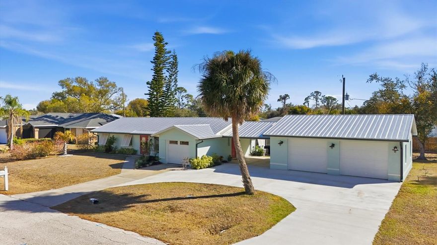 You truly have to see this one to believe it. This charming Florida pool home lives much larger than its footprint suggests. From the moment you arrive, the circular driveway and cheerful coastal colors set the tone—vibrant, welcoming, and full of personality.  Decorative Bahama shutters frame the exterior, all protected by a full metal roof replaced in 2022. A major highlight is the newly constructed 780-square-foot oversized garage (2024), offering exceptional space for vehicles, storage, hobbies, or recreational equipment. A covered portico connects the garage to the home, creating additional shaded outdoor space—perfect for a golf cart, lounge seating, or covered entry during summer showers.  Inside, the thoughtfully updated interior blends comfort and function. The cozy living room features a built-in electric fireplace, ideal for relaxed evenings. The remodeled eat-in kitchen showcases warm wood cabinetry, quartz countertops, and 2024 appliances. Extended cabinetry provides plenty of storage and flows seamlessly into the spacious dining area—perfect for gatherings and entertaining.  The home offers three bedrooms and two well-appointed bathrooms. Indoor laundry adds convenience, and a bonus flex space provides the perfect setting for a relaxation area where you can sip a beverage and catch the game. And ladies… there’s a hidden retreat just for you—but you’ll have to come see that surprise in person.  Outdoor living is where this property truly shines. The resurfaced pool (approximately seven years ago) is complemented by a travertine lanai and deck, creating a polished and inviting entertaining space. The double lot offers generous outdoor space for gardening, recreation, future expansion, or simply enjoying added privacy.. A dedicated potting shed supports gardening enthusiasts, while the custom BBQ smoke shack adds a distinctive touch for outdoor cooking and entertaining.  

This home combines charm, functionality, and thoughtful upgrades including expanded garage capacity combined with double-lot privacy position this home as a standout in its price range. Well-prepared properties with this level of improvement are limited. This is a must-see to fully appreciate the space, upgrades, and lifestyle it offers.