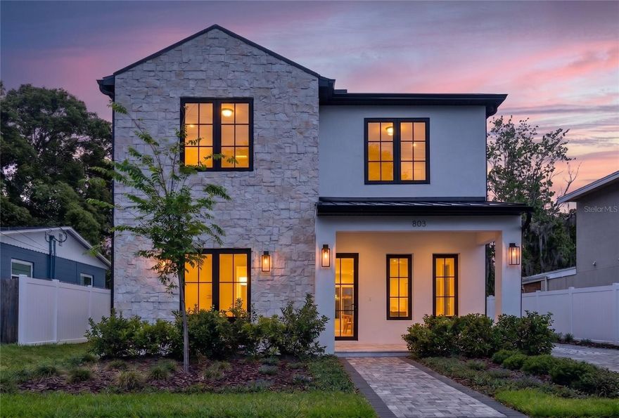 A newly constructed custom home in the heart of College Park, this residence brings together clean modern design and the character that makes this one of Orlando’s most loved neighborhoods. Thoughtfully designed with both style and functionality in mind, the main level unfolds with an effortless flow between the living room, dining space, and family room, all centered around a chef’s kitchen featuring stone countertops, a dramatic designer range hood, built-in appliances, and a wine refrigerator. A private first-floor bedroom with a full bath creates the ideal setup for guests, a home office, or multigenerational living.
Upstairs, the primary suite serves as a true retreat with a spacious walk-in closet and a spa-inspired bathroom designed with clean lines and elevated finishes. Three additional bedrooms provide flexibility for family and visitors, while the upstairs loft offers the perfect secondary living space, media room, or play area. An upstairs laundry room adds convenience to the well-planned layout.
Throughout the home, engineered hardwood flooring and porcelain tile bring warmth, durability, and timeless style. Zoned climate control, custom design details, and abundant storage further highlight the level of craftsmanship poured into the home.
Outdoor living was designed just as intentionally. Covered entertaining spaces, a fully equipped outdoor kitchen, and a professionally landscaped yard create an inviting setting for everything from quiet evenings at home to hosting friends and family. A long private driveway leads to the detached garage, a rare feature in College Park that adds both curb appeal and functionality.
Located along sidewalk-lined streets just moments from Edgewater Drive, residents can enjoy easy access to local restaurants, boutique shopping, neighborhood parks, and the highly anticipated Packing District. Move-in ready and beautifully executed from top to bottom, this home delivers a refined take on modern living in the center of one of Orlando’s most iconic neighborhoods.