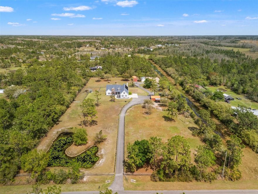 Experience refined country living at its finest on this exceptional 4.77-acre equestrian estate, where privacy, elegance, and functionality come together seamlessly. This beautifully updated 4-bedroom, 3-bath residence offers effortless one-level living with a sophisticated split-bedroom layout, abundant natural light, and stunning views of the pool and grounds from the main living areas. The spacious primary suite feels like a private retreat, featuring a generous en-suite with a walk-around shower, soaking tub, and dual vanities. The second and third bedrooms are tucked away for privacy. The fourth bedroom is ideal as an office, nursery, or guest room. The den provides a perfect space for a library, lounge, or additional office. The heart of the home is the kitchen, showcasing updated counters, backsplash, refrigerator, and dishwasher. Beautiful engineered wood floors flow through the main living spaces, complemented by tile in wet areas. The inviting family room features a wood-burning fireplace and opens to the screened-in pool and spa—solar-heated pool and propane-heated spa—creating a serene indoor-outdoor living experience.
For equestrian enthusiasts, this property is a dream. The grounds include a 100x200 riding arena, 3 dry paddocks, 4 grazing paddocks, and an open-concept barn with electricity, fans, and water. A dedicated medical isolation stall and a horse shelter add thoughtful functionality. The workshop—complete with electricity, AC, and a tack room area—has been transformed into a versatile bonus space perfect for a She Shed, Man Cave, gym, or yoga studio. Even the chickens enjoy their own well-designed coop space. The entire property is fully optimized for horses, yet equally suited for anyone seeking a private, peaceful retreat.
Additional highlights include a 3-car garage, a 2021 water heater, and a location that offers the utmost privacy while still providing convenient access to major routes. Wedgefield features an optional HOA and is just a short drive to 528, Orlando International Airport (MCO), Waterford Lakes Town Center, and UCF’s main campus.
This is a rare opportunity to own a beautifully maintained, fully equipped estate that blends luxury living with the tranquility of nature. Schedule your private showing and experience everything this remarkable property has to offer.