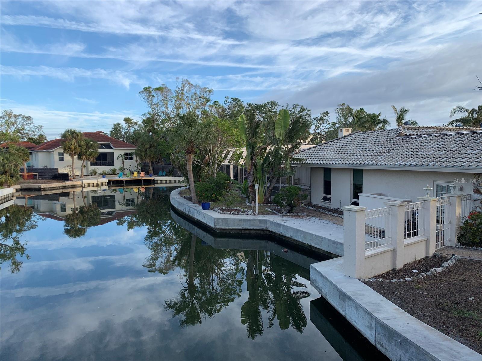 Primrose Path is a quiet street only one block long. The property has 250 feet of wide CANAL front which is extremely rare. It includes a newer extra-large cement cap. The pretty setting is next to a picturesque bridge and has another long canal view facing the front of the lot.
It is very close to Siesta village. The existing house could possibly support a second-floor addition as the first floor flooded. The area supports housing over 4 million. The owner is a licensed broker. Value is in the Land.
