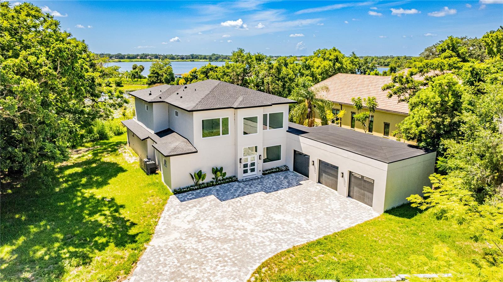 Under Construction. Luxury new construction lakefront home in Windermere, newly completed. Situated on Lake Bessie, this modern custom residence delivers architectural elegance, premium finishes, and a prime location just steps from the Town Center. The home offers 3,136 sq ft of air-conditioned space, featuring 4 en-suite bedrooms, a dedicated office at the entry, 5 full bathrooms, an outdoor shower, and an oversized 3-car garage. A dramatic two-story living area sets the tone with clean lines, expansive glass, and natural light throughout. The chef’s kitchen pairs performance and elegance, with a waterfall-edge quartz island, full-height book-matched backsplash, custom cabinetry, and high-end appliances including a Sub-Zero refrigerator, Wolf vent hood, and a full Thermador suite with double ovens and microwave drawer. A hidden walk-in pantry blends seamlessly into the design for added utility and clean aesthetics.Upstairs, the owner’s suite offers lake views, a spacious layout, and a sleek en-suite bath with a large walk-in shower and dual vanity. Secondary bedrooms include en-suite baths and reach-in closets. The home is finished with oversized rectangular ceramic tile throughout the entire main level including the expansive covered lanai and wide plank engineered wood flooring from the staircase through the second floor. Additional highlights include a glass-framed staircase and an abundance of natural light in every space. Located just blocks from Downtown Windermere, this home places you at the center of a highly coveted lakefront lifestyle. Enjoy tennis courts, playgrounds, boat ramps on both Lake Bessie and the Butler Chain, plus a vibrant local culture with weekly farmers markets, food truck nights, and seasonal events in Town Square. Cruise oak-lined sandy streets by golf cart, or explore nearby dining, shops, and fitness at The Grove and along Restaurant Row. World-class golf, theme parks, and the airport are all within easy reach and with the hard work already done, all that’s left is to move in and enjoy.
Private showings by appointment only.