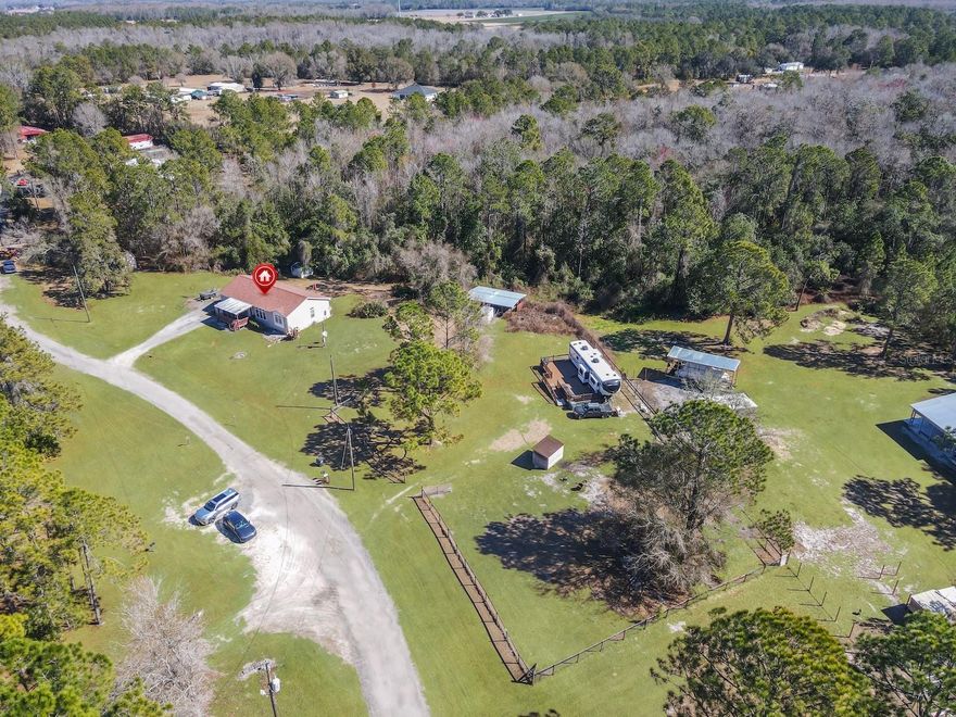 Built in 2007, this site-built modular 3-bedroom, 2-bath home is securely anchored to a concrete foundation and sits on 3 private acres. Zoned for horses and farm animals, the property offers plenty of room for an RV, boat, or additional outdoor toys—perfect for those seeking space and flexibility.  Inside, you’ll find approximately 1,800 square feet of open living space featuring 9-foot ceilings, tall interior doors, and crown molding throughout. The open floor plan is enhanced by Pergo flooring in the main living areas and ceramic tile in the kitchen.  The bedroom carpets were recently replaced 6 months ago. Stainless steel appliances are in the large kitchen and both the kitchen and bathrooms are finished with raised-panel wood cabinetry. The spacious primary suite includes a garden tub and separate shower, creating a relaxing retreat. A laundry room with extra storage adds everyday convenience.  Outdoor living shines with a large wood deck overlooking a quiet, wooded backyard. Amenities include a barn with two horse stalls. Additional upgrades include a new roof (2023) and A/C system (2019).  An RV on the property is already connected to electric and septic and features a built-on deck.  The RV does not convey with the sale. The home also includes an electric vehicle charging station. Conveniently located within approximately 30 minutes of Walt Disney World, this property offers the perfect balance of peaceful country living with easy access to major attractions, shopping, and dining. Zoned for horses, pigs and chickens, the possibilities are endless.