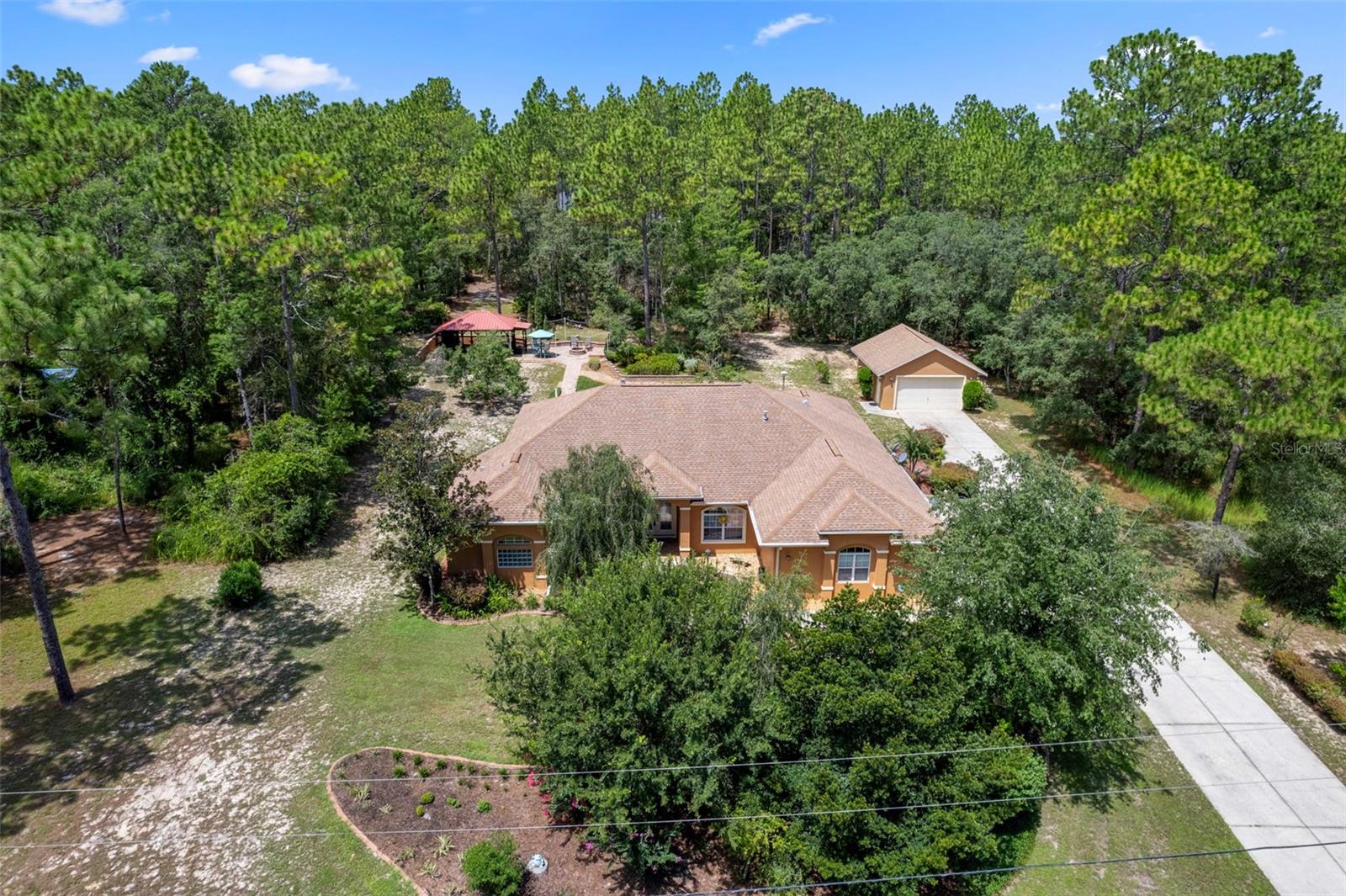 One or more photo(s) has been virtually staged. Welcome to this beautifully designed 3-bedroom, 2-bath home offering 2,303 sq ft of comfortable living space (3,237 sq ft under roof) on a sprawling 1.08-acre homesite. Built in 2007 and thoughtfully maintained, this home is move-in ready and packed with features for modern living and entertaining.? Step inside to a spacious great room with tray ceiling and crown molding, flowing into a formal dining area and a large, light-filled breakfast nook. The kitchen is a dream-efficient and stylish? - with quartz countertops, maple cabinetry, newer appliances, center island, and walk-in pantry. The laundry room adds even more function with washer and dryer, built-in cabinetry, utility closet, and folding counter.? The layout offers privacy with a split-bedroom design. A separate guest wing, tucked behind a pocket door, features two generously sized bedrooms with ample closet space and a full bath? - complete with direct access to the expansive lanai. The lanai feels like a true extension of the home, perfect for lounging, dining, or grilling in style. Just beyond, a charming gazebo offers even more space for outdoor entertaining.? The spacious master suite boasts a tray ceiling, dual walk-in closets, and a luxurious bath with dual vanities, soaking tub, and a walk-in shower with dual heads. Need a fourth bedroom, home office, or hobby space? The tiled den is ready to flex with your needs.? Additional highlights include a cozy ?gas fireplace, tile flooring in main areas, carpet in guest bedrooms and master, dual-pane windows, a new HVAC system (2023), and an oversized two-car attached garage plus a detached two-car garage—ideal for vehicles, tools, or a workshop.? Original roof and water heater? - price reflects that. Don’t miss this well-cared-for home that blends function, comfort, and charm inside and out.