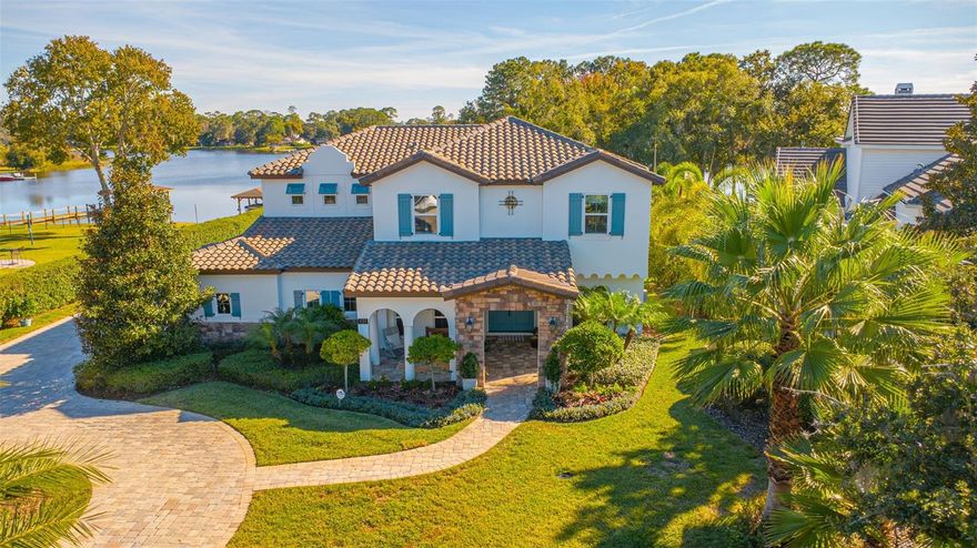 Welcome to an extraordinary lakefront sanctuary in the exclusive gated enclave of Peninsula Point in Lake Mary. Set on 2 private, fully fenced acres, this custom-built 2019 residence blends timeless Mediterranean architecture with modern sophistication—offering a resort-style lifestyle where every day feels like a getaway.  From the moment you arrive through the private gated entry, the home’s elegant circular drive, manicured landscaping, and Spanish tile roof set a tone of refined luxury. The 4,201 sq. ft. interior is filled with natural light, enhanced by arched openings, French doors, and picturesque windows framing serene water views.  Inside, hand-scraped hardwood floors flow throughout an inviting open-concept design. The formal dining room leads seamlessly into the great room, dining nook, and an exceptional custom chef’s kitchen featuring glass-accented stacked cabinetry, quartz countertops, gold finishes, GE Monogram appliances, a large walk-in pantry, and a designer wet bar with wine refrigeration—an entertainer’s dream.  The main-floor primary suite offers a peaceful retreat with lake views and a spa-inspired bath showcasing an impressive walk-through shower and luxurious soaking tub. An office/den completes the first level, perfect for work or quiet reflection.  Upstairs, three additional bedrooms are complemented by a media room with projector and an expansive game room with its own wet bar/mini kitchen. This level opens to a covered balcony with captivating views of the heated saltwater pool and spa, lush grounds, and sparkling lake—ideal for evening gatherings or quiet relaxation.

Outdoors, the home truly becomes a private resort. Enjoy multiple covered lanais, a custom built marble fireplace by the water - perfect for roasting smore's, a putting green, and a poolside bar area perfect for alfresco dining. Gentle stone steps lead down to your own private boat dock, complete with a covered lift and space for watercraft—inviting endless days of boating, fishing, and enjoying the beauty of the lake and nearby wooded island.  With a 3-car garage, ample parking, and an unmatched level of privacy, this home offers the perfect blend of elegance and ease. All of this is located just moments from A-rated schools, SunRail, and the vibrant shops and dining of downtown Lake Mary.  A rare offering of tranquility, luxury, and lakefront living—this exceptional property is more than a home; it’s a lifestyle.