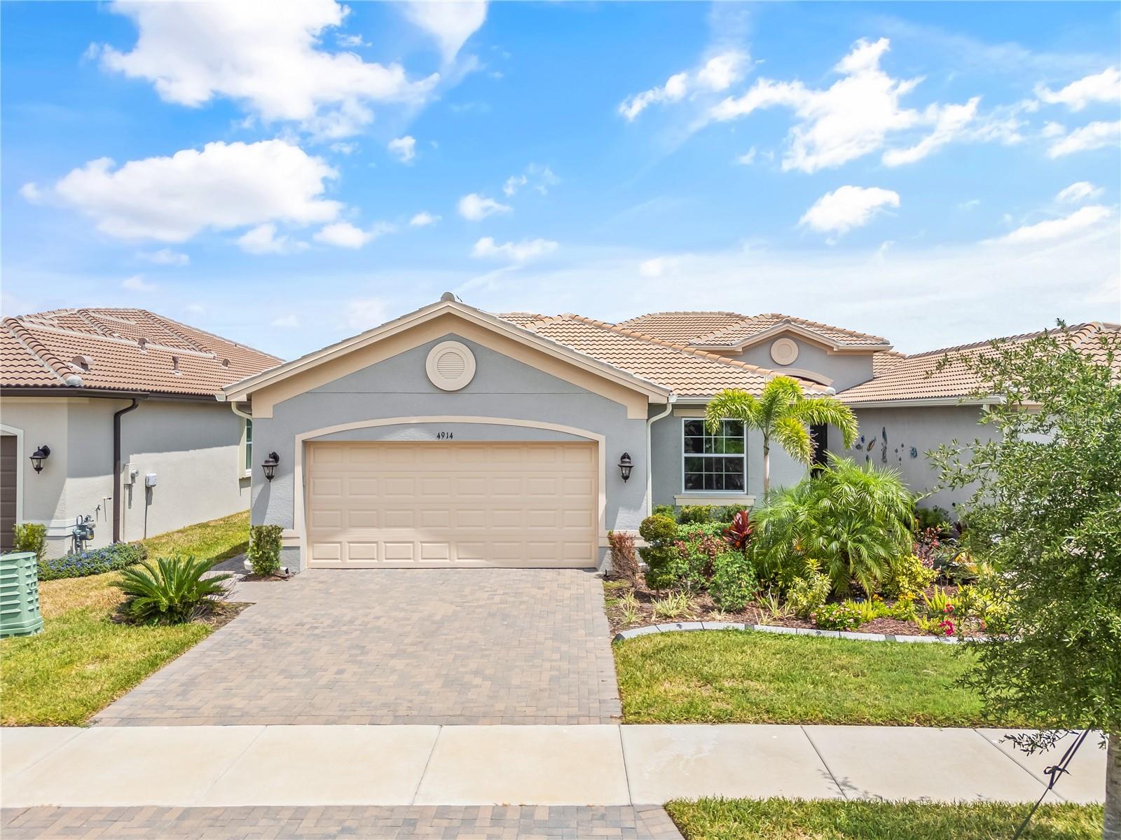 Discover the perfect blend of luxury and low-maintenance living in this stunning 3-bedroom, 2.5-bath, 2-car garage home, located in Valencia Del Sol, Tampa Bay’s premier active adult community. Just 2 years old, this home is better than new and boasts modern design and resort-style amenities with a peaceful pond view that attracts local wildlife. Featuring a tile roof, rain gutters, and a pavered driveway, this home offers excellent curb appeal and long-lasting durability. Step inside to find wide plank, brick-pattern tile flooring throughout, complemented by 5-inch baseboards, crown molding, and high ceilings. The split-bedroom layout provides privacy, with a guest suite that includes its own ensuite bath, while a double-door den can easily function as a third bedroom or office. The heart of the home is the chef’s kitchen, designed with 42” staggered upper cabinets with crown molding, stainless steel appliances, a gas range, quartz countertops, and an oversized island with breakfast bar seating. Elegant pendant lighting, a tile backsplash, and a closet pantry add the finishing touches to this bright and open space. The primary suite is a luxurious retreat, offering tray ceilings, dual walk-in closets, and split vanities with quartz countertops. The spa-like en suite features an oversized walk-in shower with a bench and floor-to-ceiling tile. From the sliding glass doors in the living area, step onto your covered, screened, and pavered lanai and enjoy the serene pond views in complete privacy. Additional upgrades include a tankless water heater, ensuring energy efficiency and endless hot water for the home. Valencia Del Sol offers unmatched resort-style amenities, including multiple pools, pickleball and tennis courts, bocce ball, a clubhouse with café, art rooms, game rooms, a fitness center, walking trails, dog parks, and over 200 social clubs. The community is ideally located near Hwy 301, with quick access to I-75, major retail and dining, beaches, and three international airports (Tampa, Sarasota, Orlando).
