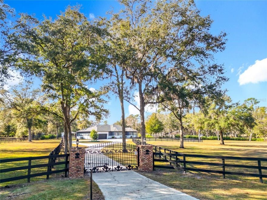 Tucked away along a quiet cul-de-sac in the equestrian-friendly McCully’s Subdivision, this impeccably maintained 4.1-acre mini-farm offers a rare blend of modern upgrades, privacy, and purposeful design crafted with both two- and four-legged residents in mind. Fenced and gated, the property welcomes you with a tree-lined driveway that leads past paddocks with new wood fencing towards the oversized garage. The home itself is incredibly eye-catching, with ample curb appeal, freshly painted exteriors, a circular drive for easy navigation, and tasteful landscaping– all surrounded by open pasture and well-seeded lawns that have been lovingly restored over time. Offering a total of 3-bedrooms and 2-baths, the home features an open floor plan with sweeping vaulted ceilings, wood-beamed accents, fresh interior paint, and engineered hardwood flooring that runs throughout. The spacious foyer opens up to the expansive great room, which centers around a striking new gas fireplace with floor-to-ceiling brickwork—a warm focal point for gatherings. The living area is nice and welcoming, complete with a built in wet-bar with plenty of storage space, ideal for those who enjoy hosting  Just beyond, the kitchen is designed for entertaining and ease of use with updated stainless steel appliances, ample cabinet and counter space, a large center island, large windows, and plenty of space for a dining set. Each bedroom is generously sized, and the primary suite includes a large walk-in closet, serene views, and a recently refreshed en-suite bath complete with new faucets and dual vanities. One of the bedrooms is currently used as a dedicated office space but features a newly added closet, offering the flexibility for use as a bedroom or a quiet workspace as desired. The lifestyle here expands well beyond the walls of the home. A sprawling screened lanai provides ample space to relax, host, or enjoy quiet mornings overlooking the land. Out back, equestrians will appreciate the attention given to the two barns on property, which provide a total of 6-stalls altogether. The barn to the right features 3-stalls which were recently dug out and reinstalled. There’s also upgraded electrical service to both barns, an electric hot water system for the wash rack, new barn fans, exterior lighting, and regular maintenance like moss spraying to ensure the health of surrounding oaks. With no HOA and zoning that supports agricultural use, this property offers freedom, utility, and a peaceful rural setting– all just a short drive from WEC, HITS, and the amenities of NW Ocala. Whether you're seeking a working horse property or a private countryside retreat with modern comforts, this one delivers both with pride of ownership at every turn.