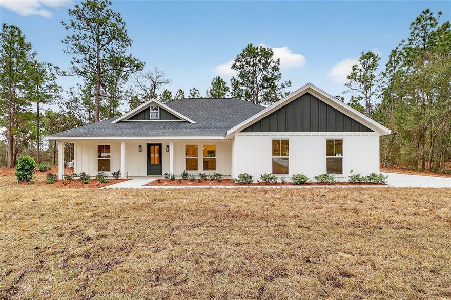 One or more photo(s) has been virtually staged. Brand new and move-in ready on a full acre in Oak Hill, an exclusive acreage community on the outskirts of Wildwood. This custom residence features board and batten Hardie siding with a modern farmhouse aesthetic, sitting on a wooded homesite with mature tree buffers and real privacy. Offering 1,691 square feet of living space and 2,516 total under roof with 3 bedrooms, 2 baths, and 10-foot ceilings in the main living areas. The primary suite features a tray ceiling, generous walk-in closet, dual vanities, and a walk-in shower. Quartz countertops, a kitchen island, stainless steel appliances, luxury vinyl plank flooring, and designer tile baths. A dedicated mud room off the garage keeps everyday life organized. Spacious two-car garage with 16-foot overhead door. Built strong with 200-amp electrical, private well and septic, and irrigation in place. Room for an accessory structure up to 900 SF for your boat or toys. Ideally located just minutes from The Villages, I-75, shopping, dining, and recreation, this is acreage living with convenience close at hand.