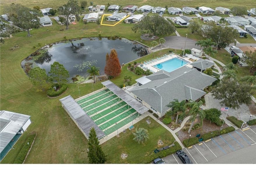 Waterfront view home on a large lot in amenity-rich community with clubhouse, pool, shuffleboard and fishing pond. This 2 bedroom 2 bathroom home features a completely remodeled kitchen with stone counter tops, custom pull-out cabinetry, and luxury vinyl plank flooring.  New carpet throughout most of home. Glass-enclosed Florida room with A/C overlooks pond and clubhouse. The guest bathroom includes a washer and dryer. Widened driveway, deep carport fits car + golf cart. Shed under a carport with water softener and storage/workshop space. Move-in ready partially furnished and conveniently located near all community amenities. Own your land in this 55+ Community. The roof was replaced in 2009.