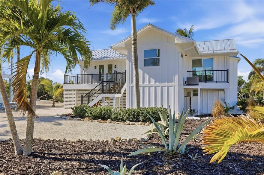 This like new home is ready to move into located on Don Pedro/Palm Island overlooking Bocilla Lagoon.
On your approach to the home, you'll see it has a recently updated metal roof. This Key West Style Home is finished in a board and baton hardy board siding with black aluminum railings.  The stairs and all decks are built with gray composite material.  The waterside open deck is12 x 24.  This offers a seating area with full waterfront views over Bocilla Lagoon for enjoying Florida sunsets with sounds of the Gulf.  There are 2000 sq feet of pavers under the home and pool area, which is great for outdoor entertaining.  There is a private wooden dock with boat lift pilings in place for a future lift.  Lush landscaping, beautifully trimmed mangroves, rip rap and large mature coconut palms are aligning the pool area.  On entering the home, the first thing you'll notice is the abundance of impact windows and glass doors which offer natural light with an open floor plan and 12' vaulted ceilings throughout.  The flooring consists of  Andare almond porcelain tile with the bathrooms done in opal white hexagon porcelain tile.  The great room which includes the kitchen that has a 4.5' x 12' long waterfall style island/breakfast bar and stainless-steel sink.  All countertops in this home are made of solid white/sparkle white quartz. All appliances are matching LG stainless steel, including the stack washer and dryer.  The wooden cabinets offer soft close cabinets.  The 12 x 20 waterfront dining area is surrounded by glass doors and windows.  The primary bedroom has water views and a private bath with floor to ceiling walk in shower with Lenox Caspian porcelain tile walls and cobalt sea pebbles hot glass mosaic flooring.  The second bedroom is directly across the hall from a full bath.   The third bedroom has its own private full bath with a tub and shower combination.  Home measures 1,347 sf - A/C, provided by Seller.  If you're looking for high end finishes and island living, you certainly don't want to miss out on this one.