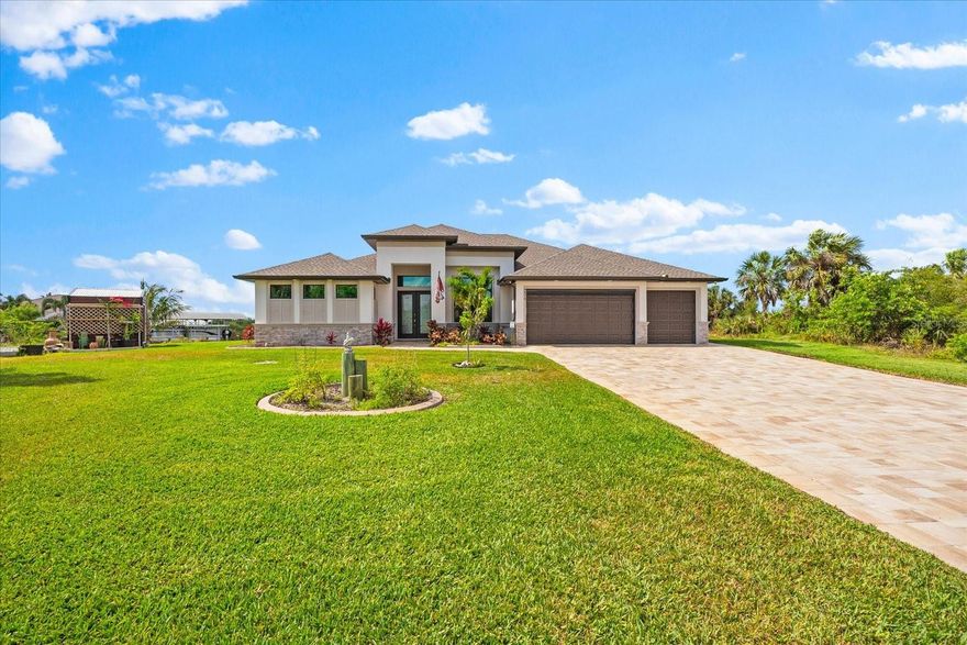 Welcome to your dream waterfront retreat in the boating community of South Gulf Cove. Situated on an oversized corner lot in an X-FLOOD ZONE, this stunning custom-built DM Dean home offers the perfect balance of elegance, comfort, and Florida lifestyle. The exterior impresses immediately with a rip-rap seawall capped in concrete, a 10x40 dock with a 10,000 lb boat lift, and a 10x10 floating kayak dock with ramp, making water access effortless. The lush St. Augustine lawn is irrigated directly from the canal, and the professionally landscaped yard is accented by an oversized paver driveway and an 8x12 storage shed for added convenience. Enjoy ultimate outdoor living with a heated saltwater pool and spa featuring a sun shelf, bench seating with jets, and decorative deck fountains—all enclosed beneath a 49-foot-wide clear view screen. The expansive 39x13 covered lanai is a true entertainer’s dream, complete with a full outdoor kitchen including a Blaze stainless steel grill, wine fridge, vent hood, and piped-in propane. A whole-house Kohler generator with 500-gallon in-ground propane ensures peace of mind, while four security cameras and a Ring-monitored system provide extra security. Step inside to discover luxury finishes throughout, including sealed travertine tile flooring, 8-foot doors, updated square trim, plantation shutters, and soaring 12- to 16-foot ceilings. The great room stuns with an enhanced coffered ceiling and 90-degree, 10-foot sliders that fully open to the lanai, seamlessly blending indoor and outdoor living. Foam insulation, a tankless water heater, Kevlar storm screen, and upgraded electrical throughout the home highlight the thoughtful attention to efficiency and comfort. A screened garage door, oversized 3-car garage, and 3-zone HVAC system add further practicality. The chef’s kitchen is both beautiful and functional, boasting solid wood custom cabinetry with soft-close features, level 7 granite countertops, GE Profile stainless appliances with induction stove, a farmhouse sink, custom glass front display cabinets, built-in spice and oil racks, and two pantries for optimal storage. Retreat to the luxurious primary suite, where you'll find a custom walk-in closet and a spa-like bathroom complete with a soaking tub, rain shower, and bidet. Guests will enjoy spacious bedrooms and a large linen closet, providing both comfort and privacy. Bonus features include multiple flat-screen TVs—85", two 65", and two 55"—along with a sound bar and subwoofer, all included with the home. This exquisite residence offers the rare combination of high-end design, thoughtful upgrades, and direct waterfront access in one of the area's most desirable neighborhoods. Don’t miss the opportunity to own this truly exceptional home.
