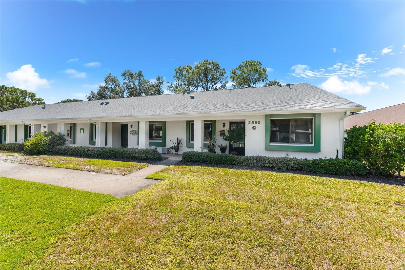 Welcome to this beautifully completely renovated villa located in Clearwater’s premier 55+ community, Village on the Green, where timeless charm meets modern updates. Offering 2 bedrooms, 2 bathrooms, and 1,030 square feet of thoughtfully designed living space, this home is move-in ready and ideal for those seeking both comfort and style. Step inside to an open-concept great room filled with natural light, seamlessly connecting the living and dining areas to create a space that is both inviting and versatile. A desirable split-bedroom layout provides privacy for owners and guests alike. Renovated in 2022 with careful attention to detail, the home showcases a coastal-inspired kitchen with granite countertops, stainless steel appliances, and sleek cabinetry. Elegant tile flooring extends throughout the entire residence, paired with fresh interior paint and an updated electrical panel, ensuring both beauty and function. The expansive screened lanai offers serene views of manicured green space, providing the perfect backdrop for morning coffee, entertaining friends, or unwinding in the evenings. An assigned covered carport with storage closet sits just steps from the front door, while ample guest parking ensures convenience for visitors. Village on the Green is known for its exceptional lifestyle amenities, including a heated lakeside pool, clubhouse, fitness center, shuffleboard courts, and a welcoming social atmosphere. Ideally located close to Countryside Mall, Mease Dunedin Hospital, Downtown Dunedin’s charming shops and restaurants, award-winning Gulf beaches, and cultural highlights like the Dunedin Fine Art Center, this villa presents a rare opportunity to enjoy the very best of Florida living in a vibrant and established community.