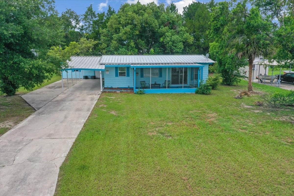 Say hello to your new get-away or investment home! This graciously updated property counts with 2-bedroom, 2-bathroom, 20x10 screened front porch, enclosed back porch, attached carport, extra detached 22x12 workshop/laundry room that can be converted into an extra leaving space. Don't let the heated SQFT fool you, this property has lot of living space with unlimited potential. Step into luxury with a relaxing front porch, perfect for gatherings while making new friends. The spacious living room seamlessly connects with the kitchen/dining area for convenient mobility. The generous primary bedroom counts with plenty of storage space, a built-in desk and en-suite bathroom. Some of the updates include Whole home water filtration, new water pump, all new flooring, Bathrooms, kitchen counters, fresh painting inside-out... No HOA, No Lease restriction, No lot rent just 365 days of peaceful enjoyment. At just a short drive from The villages, Lake Weir, Eaton Beach, Grocery shopping, hospitals and pretty much everything! Schedule your showing today!