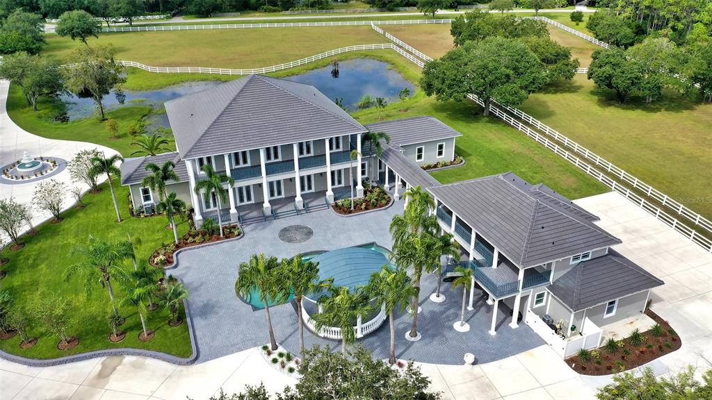 There aren't many places where you can find a tranquil "country" setting complete with horses and a big blue sky less than 20 miles from area beaches (or about 40 minutes) for when you must get some sand between your toes. This just happens to be one.
Sacrifice nothing. You can have it all. This 9+ acre estate has just been outdone with new tile roofs on all buildings, foam insulation in all attics for energy efficiency, hurricane impact windows to scare away the storms (okay, to resist winds up to 150 mph - but the other sounds much more fun), 4 new, highly efficient inverted A/C systems, beautiful new wood flooring, wood cabinetry, quartz countertops, LED lighting, walk-in closets with wood shelving, new appliances, security monitoring system with live feed, recording facility and off-site monitoring - you shouldn't need it, but if you have certain security requirements, they're already here.
You want to entertain? Media package includes TV, WiFi, Full home Audio, Lighting and other Smart Tec items or Fly your friends in. Sarasota/Bradenton International is just a short drive away and once your guests arrive they will be pleased to explore over 2700 square feet of stables and (hopefully) the five horses you choose to live in them. Never a dull moment with 5 fenced and gated paddocks with a horse training circle corral. During the day you can live out your "cowboy dreams" and in the evening play by the pool and enjoy live music (hire your favorite band - there's plenty of room in the cabana) and revel in the tranquil pastoral setting. You've earned it. Your guests will appreciate the separate guest house as they retire late into the night.
This Panther Ridge Estate is just minutes from prestigious golf courses, shopping, restaurants, and some of the most beautiful beaches in the world. If you are ready to make a move full-time you'll find Florida is one of the rare states with no state income tax and relatively low property taxes. Schedule your private showing today. Room Feature: Linen Closet In Bath (Interior In-Law Suite).