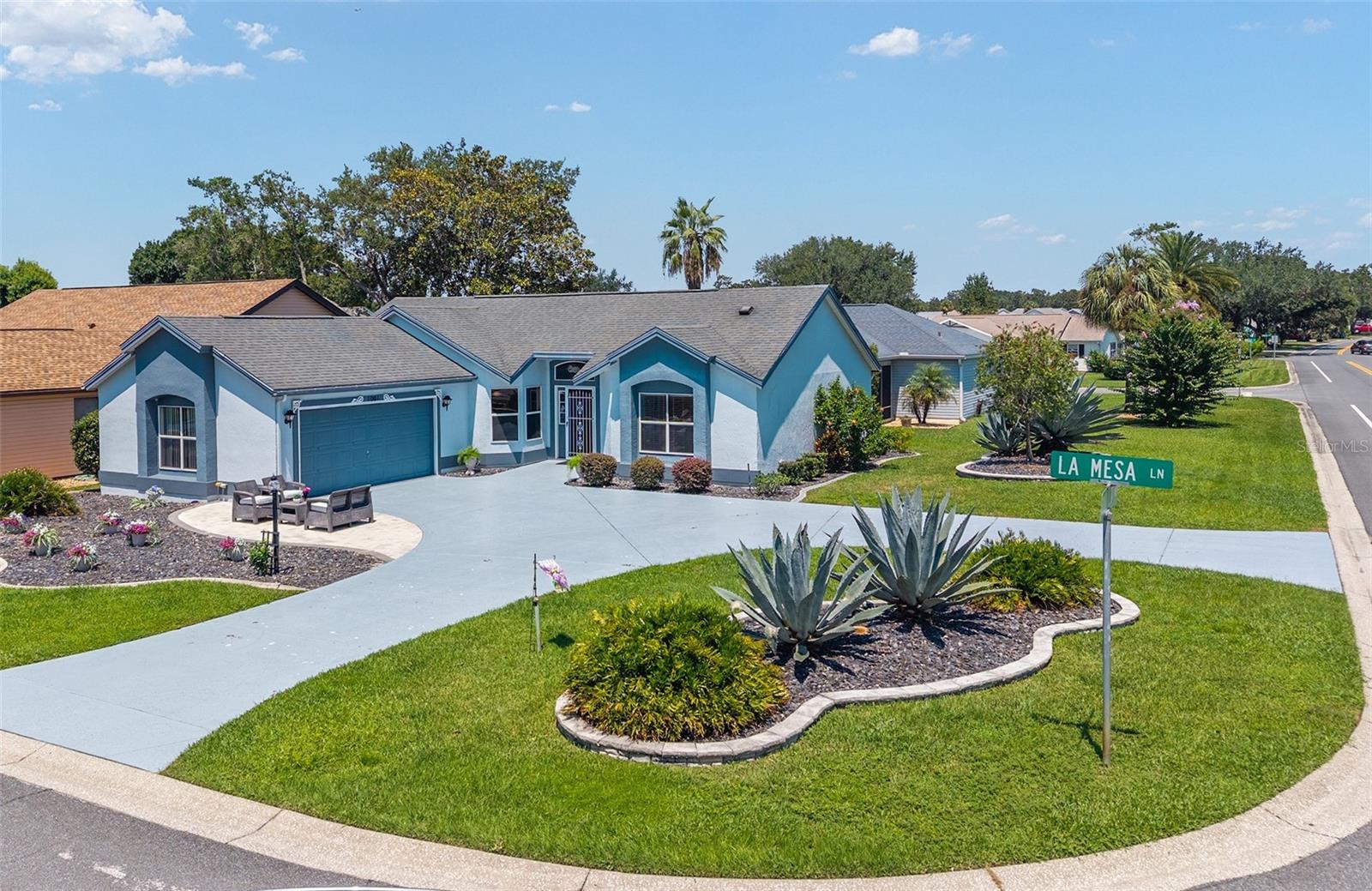 LOOK... NO BOND! Discover your next ‘Home Sweet Home’ in the charming VILLAGE of MIRA MESA—where timeless character, a quaint central location, and the active Villages lifestyle all come together!” This unique CORONADO DESIGNER w/ 2 BR / 2 BA / 2-CAR GARAGE & 1,458 SF of living area is situated on a CORNER LOT (0.168 acre). Ideally located in The Villages, you’ll enjoy everyday conveniences along the US Hwy 441/27 COMMERCIAL CORRIDOR and have easy access to SPANISH SPRINGS (4 min), LAKE SUMTER LANDING (10 min), and a short golf cart ride to multiple Rec Center Pools (adult & family) and Championship & Executive Golf Courses. Curb appeal will catch your attention first with its ARCH SHINGLE ROOF (2014), SIDE-ENTRY GARAGE featuring a highly functional semicircular drive providing easy access to either street. Next, the PAINTED DRIVEWAY & WALKWAY, mature landscaping enhanced w/ STACKED STONE HARDSCAPING & rock-filled beds, and a welcoming FRONT PATIO finished w/ pavers, the perfect perch to greet friendly neighbors on their evening stroll w/ pets, or enjoy a glass of wine and the mesmerizing Florida sunsets. The fuschia FRONT DOOR, framed by a stained glass transom & sidelight, sets a bold yet welcoming tone the moment you arrive. Step inside the FOYER and immediately notice a decorative HALF-WALL topped with MARBLE and a classic COLUMN accent, the soaring VAULTED CEILINGS, a graceful CHANDELIER, warm wood laminate floors, and an eye-catching arched column entry w/ a plant shelf above which artfully segments the open concept LIVING & DINING areas. The KITCHEN - truly the heart of this home - features VAULTED CEILINGS, wood-look TILE FLOORS, raised-panel cabinetry, striking BLACK & WHITE GRANITE countertops, and NEWER SS APPLIANCES, including a new range (2025). A French door refrigerator, undermount SS sink w/ pull down faucet, and raised PENINSULA BREAKFAST BAR add both function and flair. The sunny BREAKFAST NOOK flows into the 18' x 12' FLORIDA ROOM (under heat & air) creating a multi-purpose space year-round, ideal for reading, crafting, afternoon puzzles, or hosting card games with friends. From here, dual sliding glass doors open to the 8' x 28' SCREENED BIRDCAGE PATIO - an outdoor retreat designed for balmy winter mornings with coffee, alfresco dinners with friends, or quiet evenings under the stars—always enjoyed in privacy behind the lush rear hedge.. Moving inside to the east wing of the home, the PRIMARY SUITE is your private retreat, designed for both comfort and style w/ VAULTED CEILINGS, a decorative plant shelf accent above, a double window allowing natural light, and a WALK-IN CLOSET. The ENSUITE BATH boasts dual sinks, GRANITE COUNTERTOPS, white cabinetry, PRIVATE WATER CLOSET, and a TILED WALK-IN SHOWER w/ a frosted glass door and mosaic tile floor. The GUEST BEDROOM offers a peaceful view of your beautiful front yard, ample closet storage and an adjacent FULL BATH featuring a tub/shower combo & a decorative tiled vanity/sink. Other perks include: HWH (2020), updated garage door springs/motor/belt (2025), and attic pull-down stairs & utility sink in the garage. This is more than just a house—it’s your passport to the unmatched VILLAGES LIFESTYLE of complimentary year round executive golf on 42 courses, countless rec centers, and 3,000+ social clubs at your fingertips. Don’t miss this opportunity to claim your own SLICE OF PARADISE! Schedule your private showing today and start living your dream retirement lifestyle!