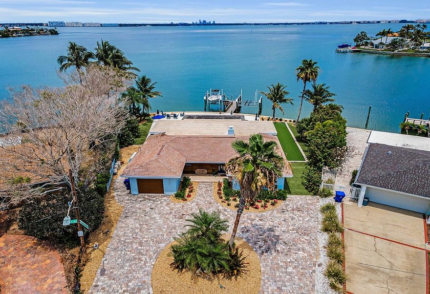 LOCATED ON BEAUTIFUL OPEN WATER WITH VIEWS OF DOWNTOWN ST. PETESBURG IN THE DISTANCE, THIS WONDERFULLY UPDATED AND COMPLETELY RENOVATED HOME IS THE PICTURE OF COASTAL CONTEMPORARY ELEGANCE! Its surprisingly large lot enjoys a sweeping 133ft of seawall – offering tremendous waterviews, day and night. A fine brick paver circular driveway and easy maintenance zeroscape landscaping introduce a residence with a rich modern appeal. Beyond its well-finished covered entryway, discover a terrific open great room plan with lovely driftwood-style porcelain floors and stunning view of your waterfront. Your exquisite chef’s kitchen boasts impressive quartz surfaces, coastal white shaker-style cabinetry, Viking stainless steel appliances, herringbone-pattern backsplash, and a huge island bar with prep/work center. Exceptionally-finished wood burning fireplace transitions to a gorgeous living room that overlooks the pool deck and waterfront. The wide bank of living room sliding glass doors pocket into the wall, enabling a fabulous indoor-outdoor living experience! Double doors introduce the lavish owner’s suite with views of the intracoastal waterway and private access to the swimming pool deck. The owner’s bath is a sumptuous delight, with alluring quartz surfaces, spacious dual vanities, a resplendent walk-in glass shower enclosure with dual shower heads and dazzling tilework, and a luxurious walk-in closet system. The second bedroom suite is private, with update full bath. The third bedroom is oversized, with an adjacent full guest bath that is also gracefully updated. Step out back to a true waterfront paradise with spectacular panoramic views of the intracoastal waterway. Built-in outdoor gas cooking center with bar seating and granite surfaces, supports a 320sqft covered dining/lounging deck. A huge shellstone paver deck encircles a dazzling Pebbletec pool and spa with in-pool sunshelf. Located near the water, the built-in gas firepit is a perfect night-time spot for lounging and casual conversation. With artificial grass, palms and various plants – this is a very easy home to maintain. Your composite dock features a fish cleaning station, step down for kayak/paddleboard launch and two boat lifts including a 20,000 lb boat lift; from here, you are less than a 10-minute boat ride to the Gulf. Easy access to downtown St. Pete and Tampa International Airport. Recognized as one of America’s best beaches, St. Pete Beach offers exceptional dining, shopping and entertainment. An outstanding waterfront value and a great location to live, work and play. Dimensions are estimates, buyer to verify.