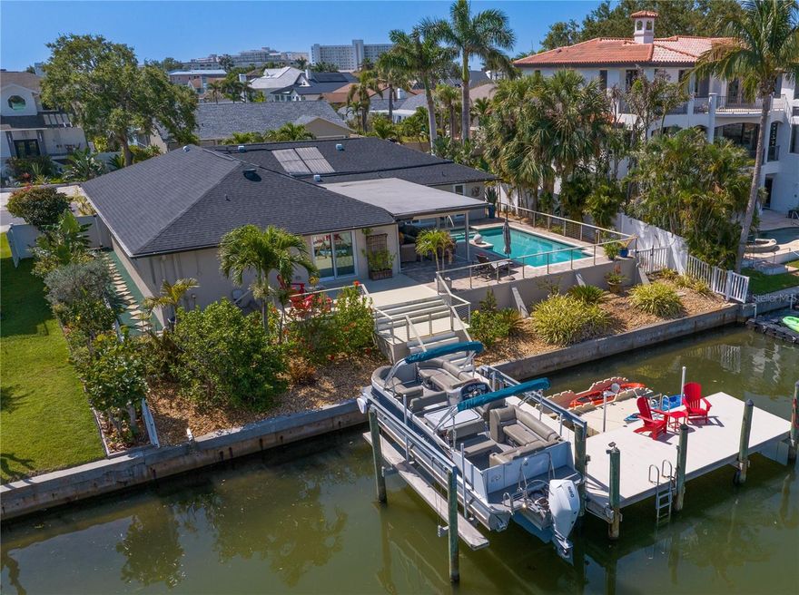 Welcome to this stunning single-story waterfront residence, located within the highly sought-after gated community of Pasadena Yacht & Country Club.  Offering 4 bedrooms, 3 full baths, and 2,618 square feet of refined living space, this home masterfully blends luxury, comfort, and effortless indoor-outdoor living.  Step inside to discover a spacious, open-concept layout with soaring ceilings, elegant high-end porcelain tile flooring, and a split-bedroom design ideal for privacy and entertaining. The great room is a showpiece, featuring pocketing sliding doors that extend your living space onto an expansive covered patio—framing peaceful waterfront views and inviting cool breezes from Boca Ciega Bay.  An outdoor kitchen extends the culinary experience, making al fresco meals and poolside entertaining effortless.  Electric Kevlar screens frame the patio and expand the living area providing additional storm protection.  The heart of the home is the stunning chef-inspired kitchen, with custom cabinetry, GE Café appliances, Taj Mahal quartzite countertops, and a generous center island perfect for casual dining. An adjacent brasserie barroom adds to the ease of entertaining. The primary suite is a private retreat, complete with its own waterfront deck, a spacious walk-in closet, and a luxurious en-suite bath featuring dual vanities with marble counters and a frameless glass shower. Three additional bedrooms provide ample space for guests or family.   Outdoors, enjoy a solar-heated pool, built-in summer kitchen, and direct access to the bay via your private dock with a 10,000 lb boat lift, floating kayak dock, underwater fish lighting, and accommodations for your large boat. This home is fortified with hurricane-impact windows, tankless water heater, solar attic fans, and a whole-house water softener system for year-round comfort and protection.  New Roof - 2025 and new garage coating on floors.  This home was HIGH AND DRY .  As a resident of Pasadena Yacht & Country Club, you’ll have the opportunity to circumvent the club waitlist and enjoy world-class amenities including golf, tennis, pickleball, a protected marina, fine and casual dining, and a bayfront pool and clubhouse.  All of this is just minutes from the sandy shores of St. Pete Beach, the vibrant energy of downtown St. Petersburg, and quick access to I-275 and US 19 for easy travel throughout the Tampa Bay area. Tampa and St Pete airports are conveniently located.