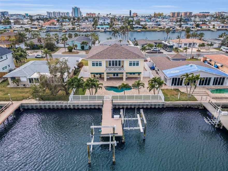 Built-to-last above base flood elevation with all block construction and poured concrete floors, you’ll appreciate the peace of mind offered by this exceptional waterfront residence.  A spacious brick paver driveway, generous 6-car garage parking, and two 10,000 lb boat lifts make this the perfect place for your vehicles and watercraft.  Driftwood-style porcelain floors, lovely crown woodworking and tall 10ft-high ceilings introduce a wonderful open floorplan with beautiful views of the waterfront.  Your spacious living room opens to an elegant 225sqft covered balcony with a built-in electronic sunshade.  Fabulous chef’s kitchen boasts fine quartz counters/backsplash, rich coastal cabinetry, huge wrap-around multi-level breakfast bar, under and above cabinet lighting, and pantry closet.  Double doors open to a fabulous waterfront owner’s suite that opens to the waterfront balcony and features two walk-in closets with built-in dressers.  Owner’s bath provides dual quartz vanities and an exquisite designer walk-in shower with seating bench. Second bedroom is oversized and en suite, and has a graceful bath with jetted tub and shower. Third bedroom is spacious and has a walk-in closet with adjacent full guest bath.  Out back discover a huge 470sqft covered deck that transitions to a large paver area with a gorgeous Pebbletech Pool/Spa.  Deck offers lots of lounging space and covered outdoor dining.  Updated seawall supports a composite dock with two boat lifts.  Bahamian shutters on the outside, plantation shutters on the inside, large and well-finished laundry room with extensive cabinetry storage, lower-level multi-purpose area, large 8ft-high elevator, PVC privacy fencing, and so much more.  Located within easy walking distance of the beach, dining and entertainment.  An outstanding value in an excellent waterfront boating community!  Buyer to verify all dimensions. Bathroom Mirror does not Convey.