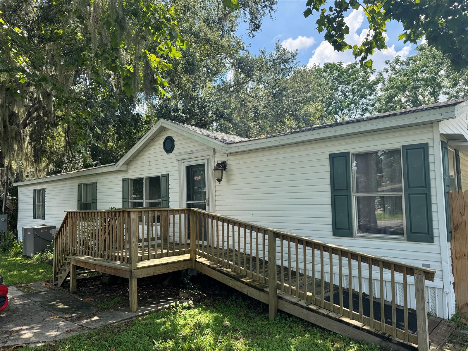 1999 double-wide with addition, 1728 sq ft on 0.34 acres. No HOA, Lake Harris access with boat ramp two houses away. Plenty of room to store your boat and other toys. Features 2020 AC, 2023 roof, wood-burning fireplace/chimney in good condition, new water filtration system (well/septic). Four spacious bedrooms, stunning master bath and walk in closet. Large, fully fenced back yard, two outbuildings, carport. Needs some TLC: subfloor was replaced in living room and den, needs new flooring in living room, den, kitchen, new carpets needed in bedrooms, needs new countertops or tile repair and there are some broken window panes. The back deck was removed as it was causing a leak. ARV: $230,000. Needs $25k-$30k repairs. Renovation loans, cash, or hard money.