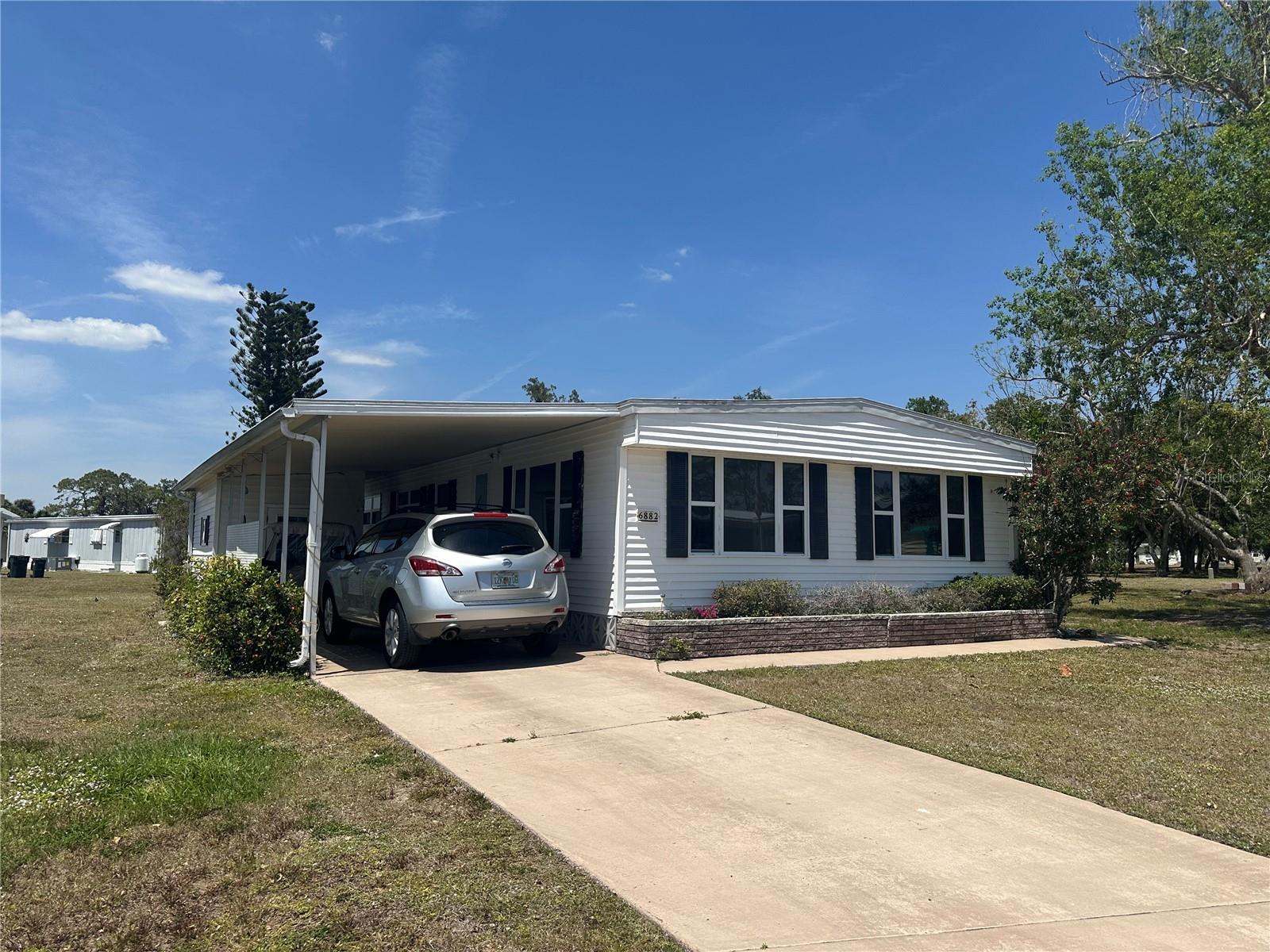 Great opportunity to own a home in affordable Holiday Park, North Port FL. A 55+ community, pet-friendly with land ownership. LOW maintenance/recreation fee included in the property tax bill annually at $2,340.00, NO HOA and NO CDD fees! Spacious double wide home sited on a pie shaped cul de sac lot. Home with 3 bedroom 2 full baths. Large living room with built in shelving and large cabinet storage space. Large eat in kitchen with kitchen island. Enjoy the Florida room off the kitchen. Large hall full bath with tub/shower and many cabinets. Exterior door to a full screened cage. Large Primary bedroom with full bath with beautiful tile and stone flooring shower. Many closets in bedroom. Extra long carport and storage shed for more storage. Many possibilities with this large home. Schedule your private showing today!
Holiday park community includes lots of recreation with tennis/pickleball courts, horseshoe pits, bocce-ball plus with a clubhouse with 2 pools. Conveniently located in North Port's central shopping district. Downtown Wellen Park, Braves practice stadium plus the new Costco and guld coast beaches just minutes away. North Port Marina Park-public boat ramp/canoe/kayak launch is minutes away from the parks back entrance.
Come check out this spacious home!