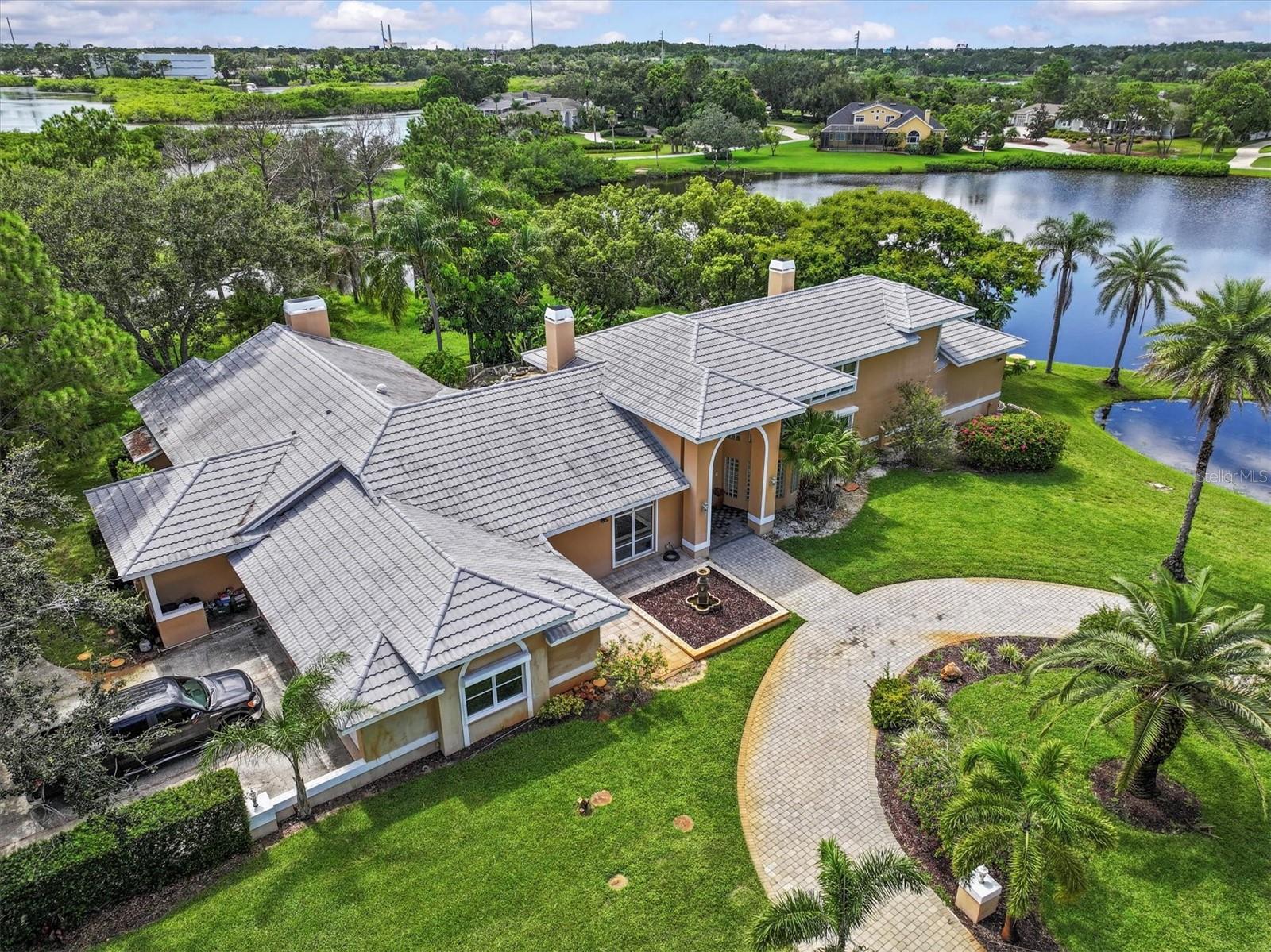 Wow! Beautiful 2 pond views! If you’ve been searching for a spectacular home at an incredible value, your opportunity has arrived. Welcome to 1520 Jade Lane, located in the exclusive and rarely available community of Sail Harbor. Tucked between the serene banks of the Anclote River, this hidden gem offers direct access to the Gulf of Mexico by boat. The neighborhood includes a public boat ramp, so feel free to bring your vessel and start enjoying the waterfront lifestyle. Surrounded by multimillion-dollar waterfront estates, this property stands out as a true value in an elite setting.
This impressive home spans over 5,000 square feet and is situated on a sprawling 1.11-acre lot with views o 2 ponds. It features a three-car garage, two spacious driveways, and a resort-style swimming pool with rock waterfall ideal for entertaining. The entire home is protected by motorized hurricane shutters that ensure peace of mind. Inside, you’re greeted by soaring vaulted ceilings, an open floor plan, and stunning views of the pool from the moment you enter. The cozy fireplace adds a welcoming touch to the main living space.
The private master suite is located on the upper level and includes its own balcony, a spacious bathroom, a fireplace, and two large walk-in closets. On one wing of the home, you’ll find the family room and a generous kitchen with granite countertops that overlooks both the pool and the living areas, along with a charming breakfast nook. This side of the home also features a bedroom, a full bathroom, and an expansive bar and bonus area—perfect for entertaining or a pool table.
The opposite wing includes several additional bedrooms, another full bathroom, and a massive storage room. At the end of the hallway, a large addition offers an oversized bedroom that could easily serve as a second master suite. This room boasts breathtaking views of the two ponds on the property and offers picturesque sunsets that make it truly special.
The home comes equipped with a central vacuum system, a durable metal roof installed in 2011 with a limited warranty through 2031, four A/C units installed in 2013, and a hot water heater added in 2016. Other amenities include fenced in yard for dogs or play area, 2 circular driveways, 3 car garage and parking for boat/RV
This home had a repaired sinkhole, which occurred due to construction equipment used during an addition in 2001—not due to natural causes. The issue was professionally repaired over a decade ago, and full engineering reports are available for review.
Don’t miss your chance to own this incredible home in one of the area’s most desirable and private communities. Zoned for top-rated Pinellas County schools, Low HOA and a friendly, well-kept community. Located just minutes from the Gulf beaches, historic downtown Tarpon Springs, the famous Sponge Docks, and countless dining, shopping, and recreational options, this home is perfectly situated for Florida living at its best. Seller is motivated bring all offers.