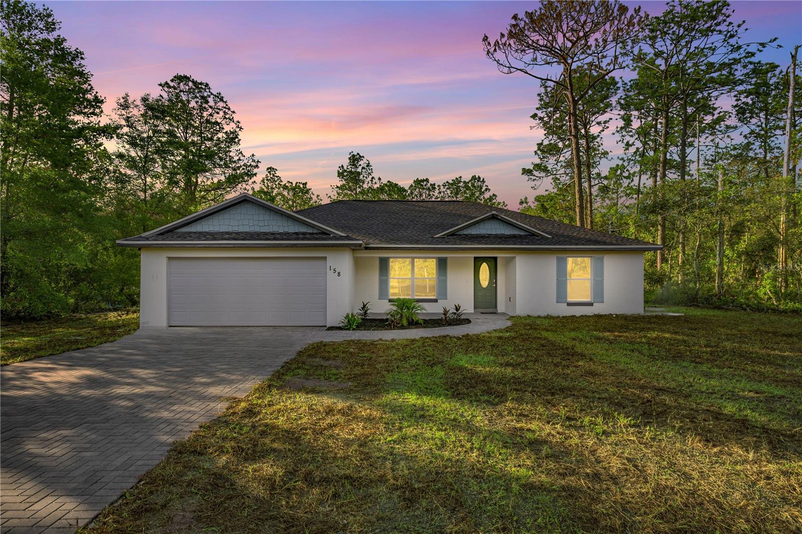One or more photo(s) has been virtually staged. Welcome to a one-of-a-kind new construction home in Southeast Ocala that breaks away from the ordinary! This beautifully designed 3-bedroom, 2-bath residence offers stylish upgrades and thoughtful touches throughout. From the moment you arrive, the paver driveway and walkway hint at the attention to detail that continues inside. The open floor plan features a spacious kitchen with a large island, dual sinks, and a window perfectly placed to overlook the backyard grounds—ideal for both entertaining and everyday living. The interior boasts mid-century modern finishes, including upgraded interior and closet doors, unique lighting fixtures, and a mix of earthy greens and natural tones that create a calming, elevated vibe. The primary suite is a true retreat with a tray ceiling, dual vanities, a large walk-in shower, and a built-in closet system designed for optimal organization. Step out back and enjoy the paver entertainment area—perfect for gatherings or quiet evenings under the stars. If you’re looking for new construction that stands out from the crowd, this is the one for you.