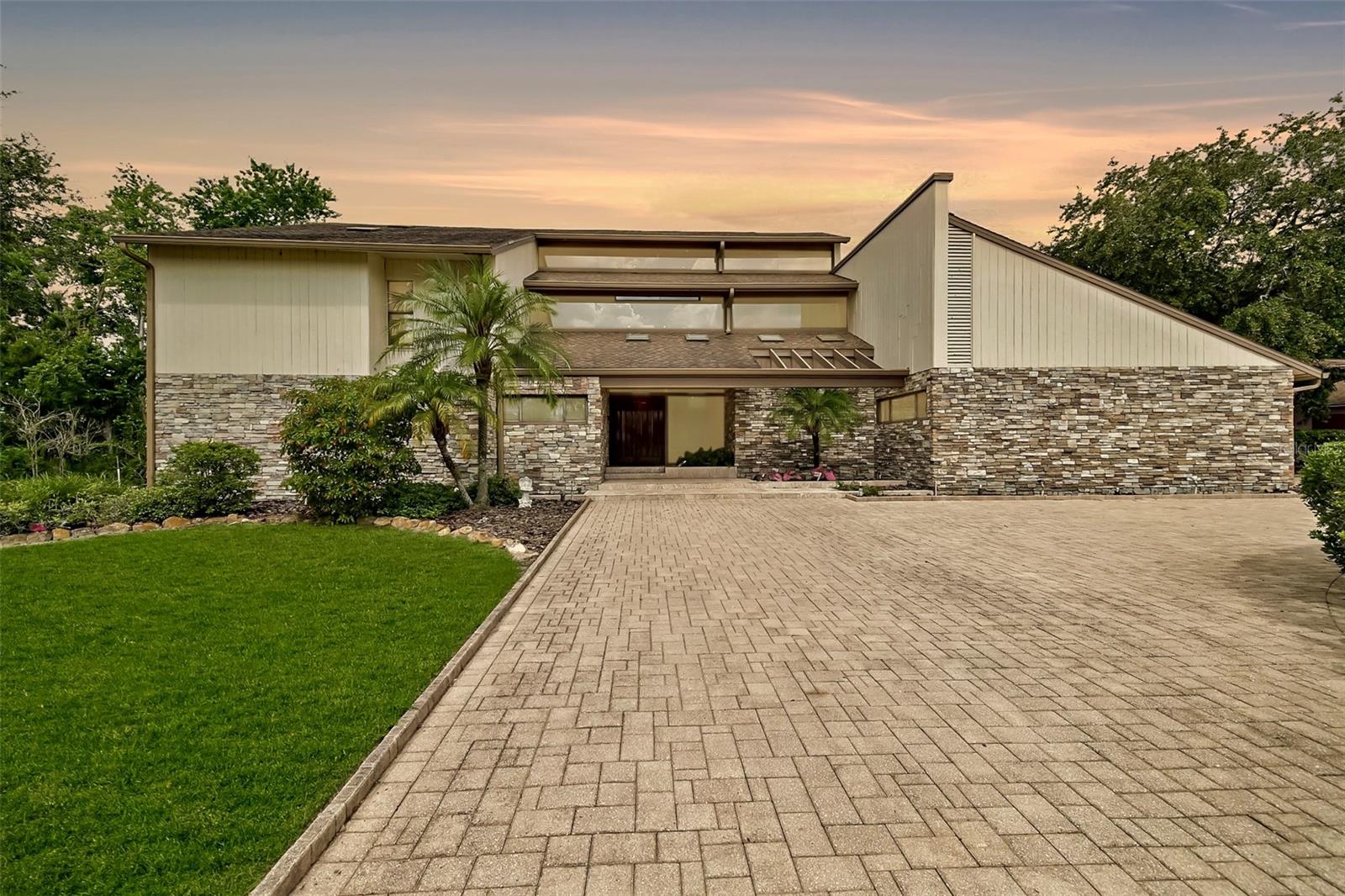 Live the Lakefront Dream! This extraordinary estate isn’t just a home — it’s a lifestyle. A rare blend of modern design, natural serenity, and architectural brilliance, this 4 bedroom, 4 bath retreat with an office, game room, resort-style pool and 3 car garage redefines lakefront living. Every detail of this home has been masterfully curated, from the contemporary exterior with steel frame construction and stacked stone accents to the pavered circular drive and a lush landscape bordered by both lake and pond views. Upon entering an elegant foyer with travertine flooring, you'll discover the breathtaking living room with a soaring two-story ceiling, warm hardwood floors, a stately fireplace and an awe-inspiring 25-foot wall of glass that invites in the shimmering beauty of Walden Lake, wrapping the space in natural light and unforgettable views. Whether you're hosting friends or savoring quiet moments, the heart of this home is made for connection. Crafted with discerning attention to detail, the exquisitely appointed chef’s kitchen features two oversized granite islands, rich cherry wood cabinetry, gleaming hardwood floors, exposed wood beam ceilings and a Tuscan inspired range hood that adds rustic charm to the modern design. Premium Sub Zero and Thermador appliances, multiple prep stations and a temperature controlled walk-in pantry/wine room elevate everyday cooking to a gourmet experience. Adjacent is an inviting breakfast nook with built-in banquette seating plus a secondary prep area with a built-in microwave, sink, dishwasher and bar cabinetry. Also on the main floor you'll find a sophisticated formal dining room, a versatile 2nd bedroom/bonus room, a large game/bonus room with picturesque water views and screened patio, and a gracious guest suite with an elegant full bath that provides a private retreat. Upstairs, your private oasis awaits. The primary suite is nothing short of breathtaking — panoramic water views, a dramatic floor to ceiling stacked stone fireplace, custom cherry bookcases, and a private screened balcony with a soothing jacuzzi and sunset views create the ultimate retreat. The ensuite bath is pure indulgence: a relaxing soaking tub, huge walk-in granite shower, dual vanities with make-up area, water closet with bidet, and a dream-worthy enormous 21 foot walk-in closet with custom wardrobe system designed to impress. An adjoining office makes working from home a breeze. A temperature-controlled wine room, secondary bedroom with private balcony and full bath with large walk-in shower completes the upper level. And then… there’s the outdoors. Step into your own private resort: a two-story screened flagstone lanai, a dramatic lagoon-style pool, and a magnificent stacked stone waterfall wall that soothes the soul. A cedar and granite summer kitchen, elevated lounge terrace, dedicated pool bath and spiral staircase connecting both levels make this the ultimate space for entertaining, relaxing, or simply breathing in the beauty around you. 2015 Roof, one AC is 3 -4 years old, two 2023 new water heaters, home replumbed in 2023, 2024 Sub zero refrigerator, 2024 new screen for screen enclosure, 2025 new waterfall pump. If you’ve been waiting for something extraordinary, your moment has arrived.