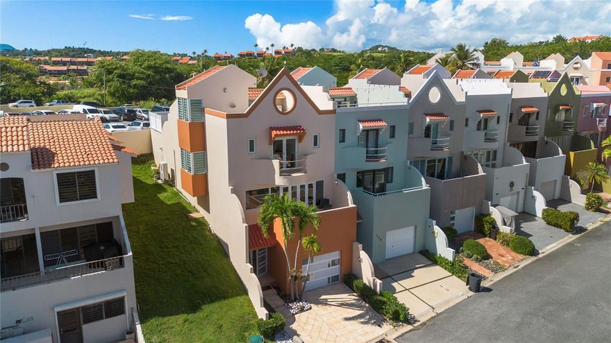 Monte Carlo Townhouse – Urbanización Palmanova, Palmas del Mar

Discover this elegant three-level villa located on Monte Carlo Street within the private gated community of Urbanización Palmanova in Palmas del Mar.

The first level features an inviting entrance foyer and a spacious two-car garage with storage area.
On the second level, the main living quarters open into a bright, open-concept floor plan that seamlessly connects the living room, dining area, and kitchen. Expansive glass doors lead to a balcony overlooking partial views of the beach and the El Yunque mountains, creating a perfect indoor-outdoor flow. This level also includes a half bathroom and access to a beautiful private pool with cascading waterfall—ideal for entertaining and relaxation.

The third level offers three bedrooms and two bathrooms, each with its own balcony for natural light and breeze. A staircase leads up to the rooftop terrace, perfect for enjoying sunsets and the resort views.

Located within Palmas del Mar, residents enjoy access to world-class amenities including two championship golf courses, a tennis and pickleball club, beach club with restaurant, equestrian center, marina, school, and over 20 dining options throughout the resort.